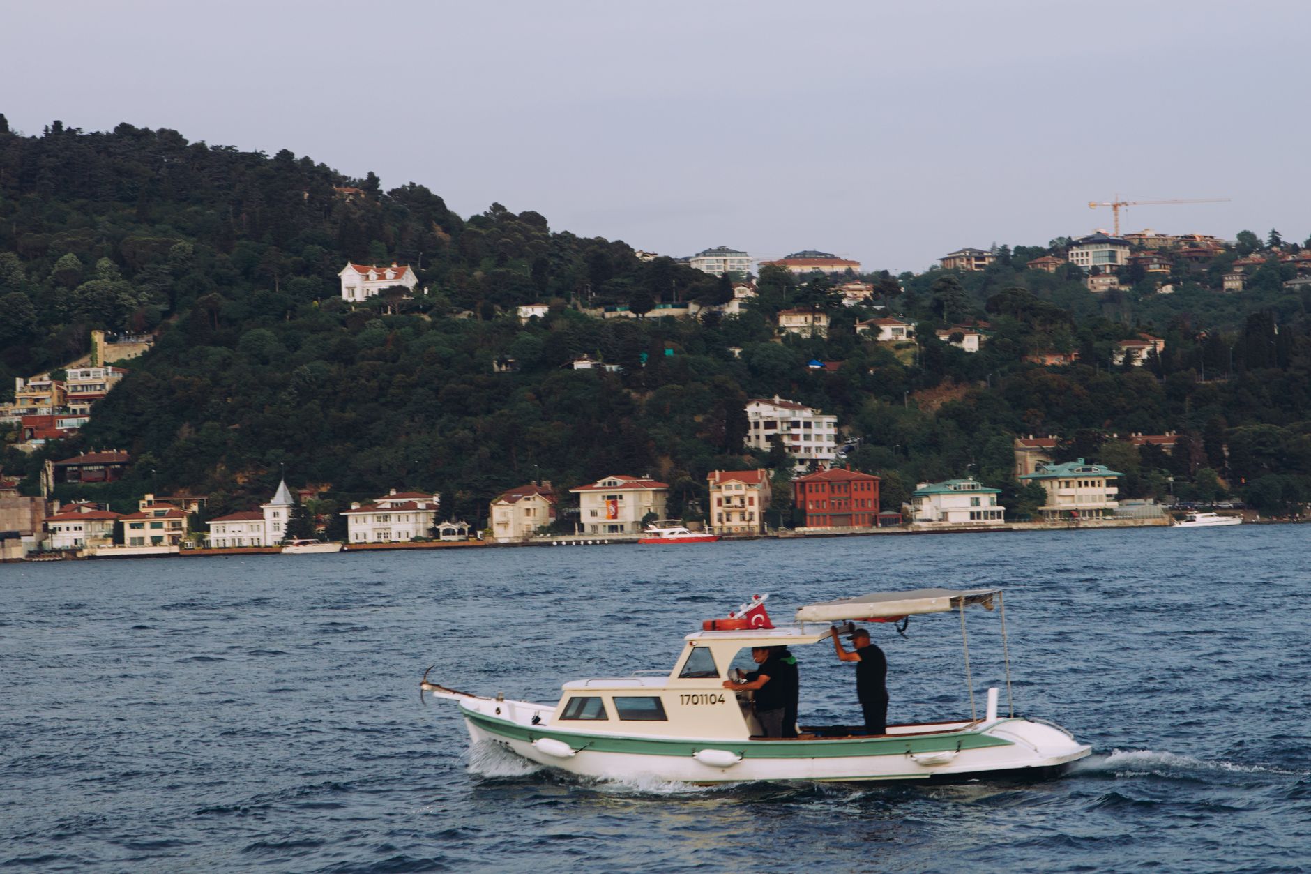 A tranquil scene on the Bosphorus featuring a boat and hillside homes in Istanbul.