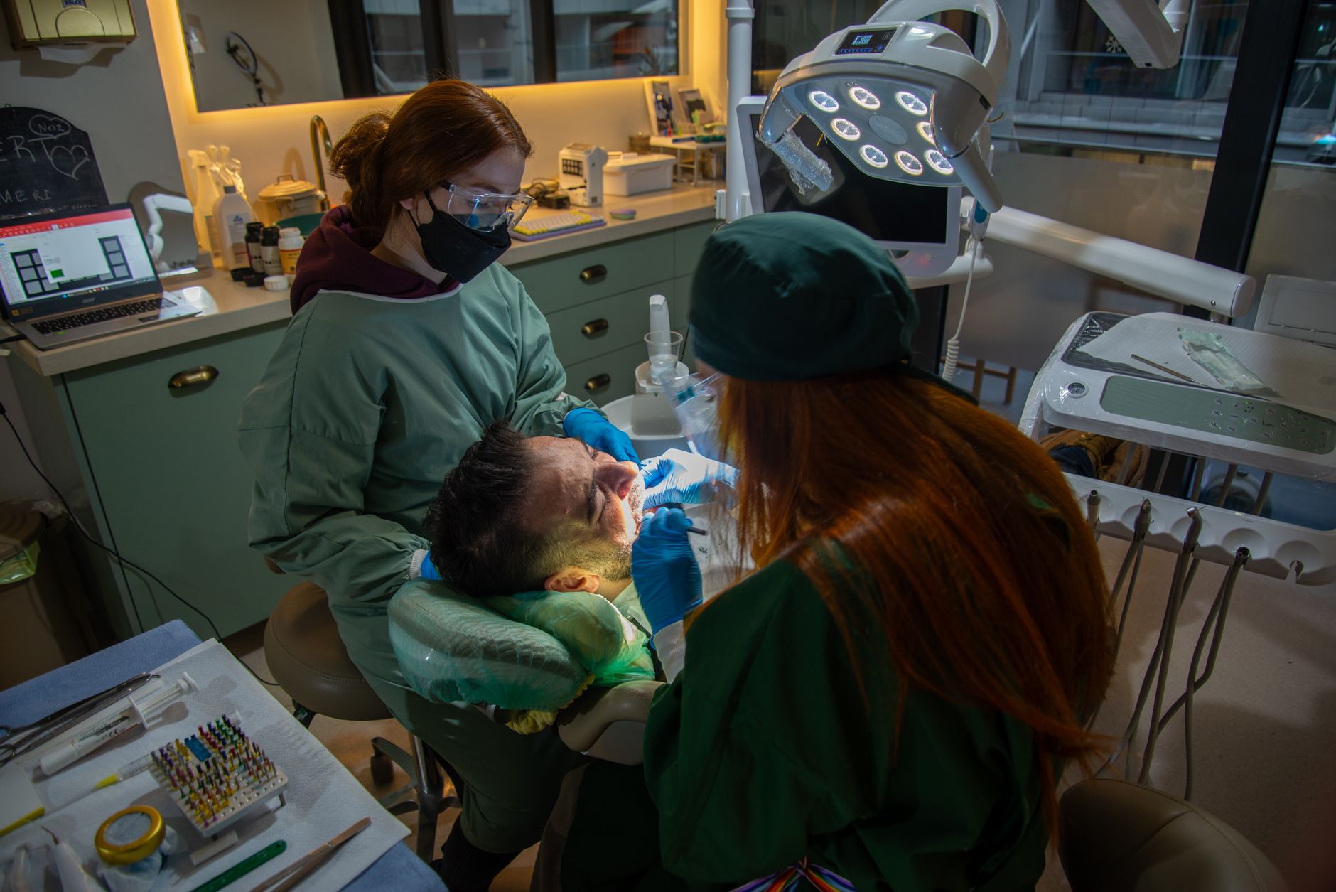 A maxillofacial surgeon and assistant performing jaw surgery in a clinic.