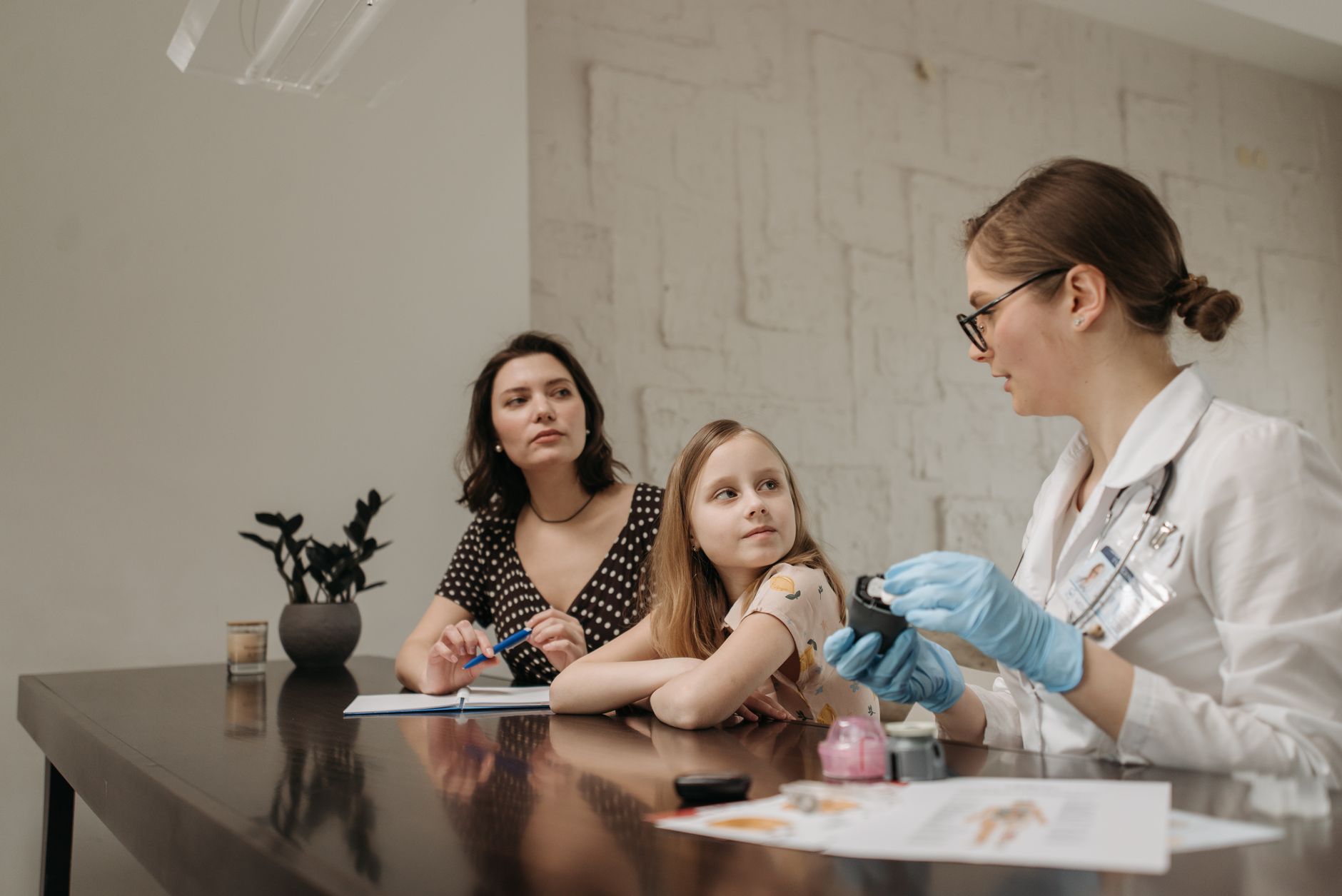 A paediatric neurologist discusses treatment options with parents and a child in a consultation room.