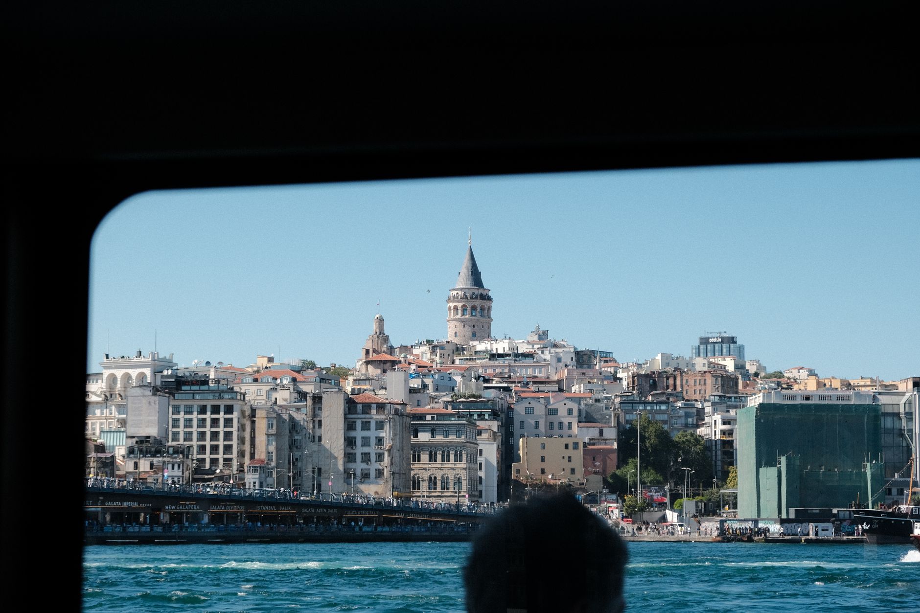 A view of Istanbul's skyline featuring the Galata Tower from a window, capturing a serene moment.