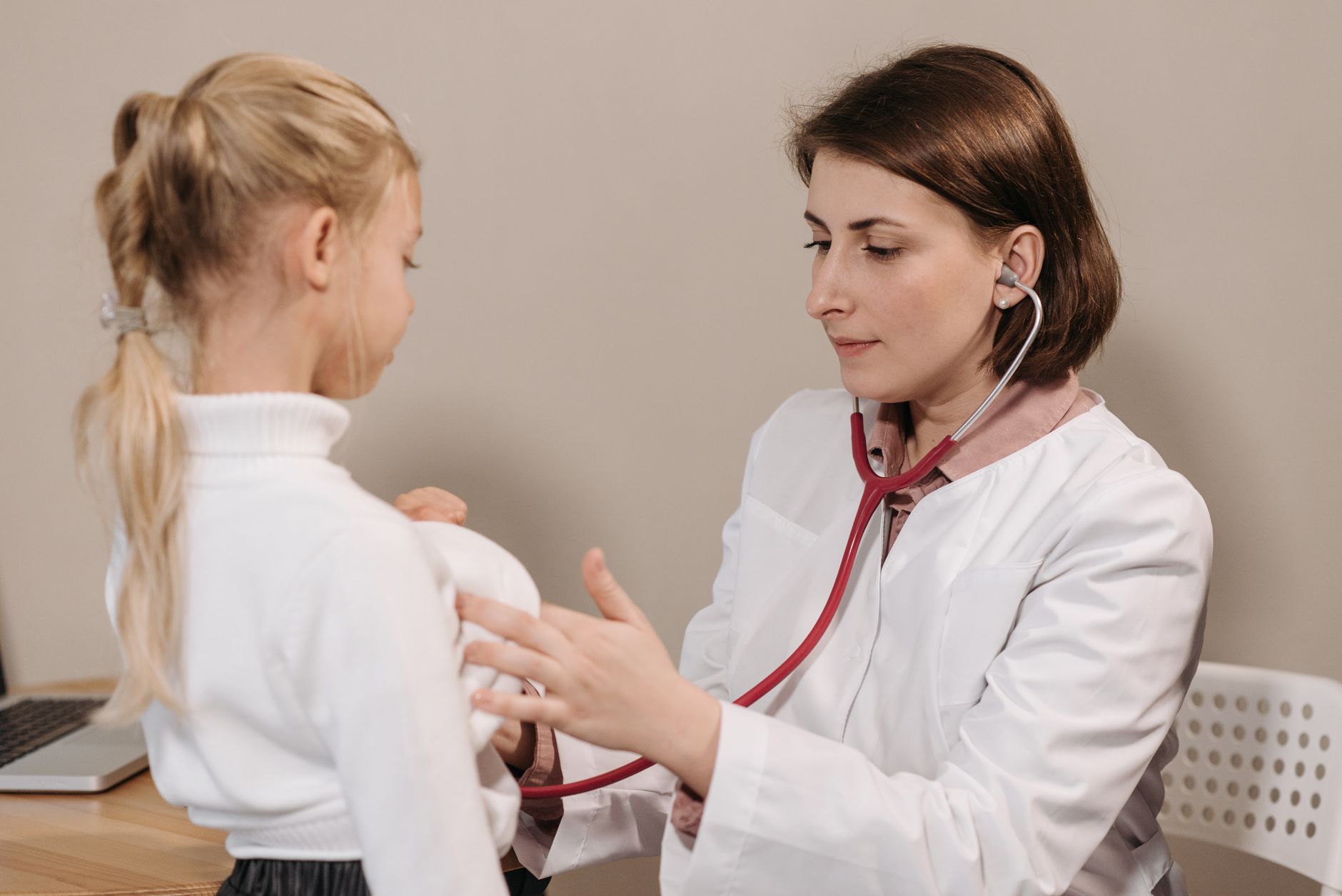 A paediatrician examines a young girl during a consultation in a medical clinic.