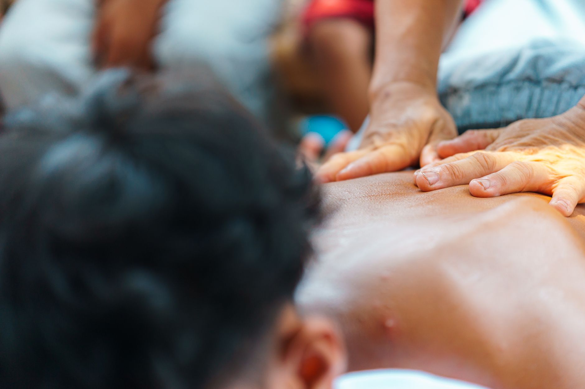 A therapist applies hands-on therapy to a child's back in a colorful rehabilitation setting.