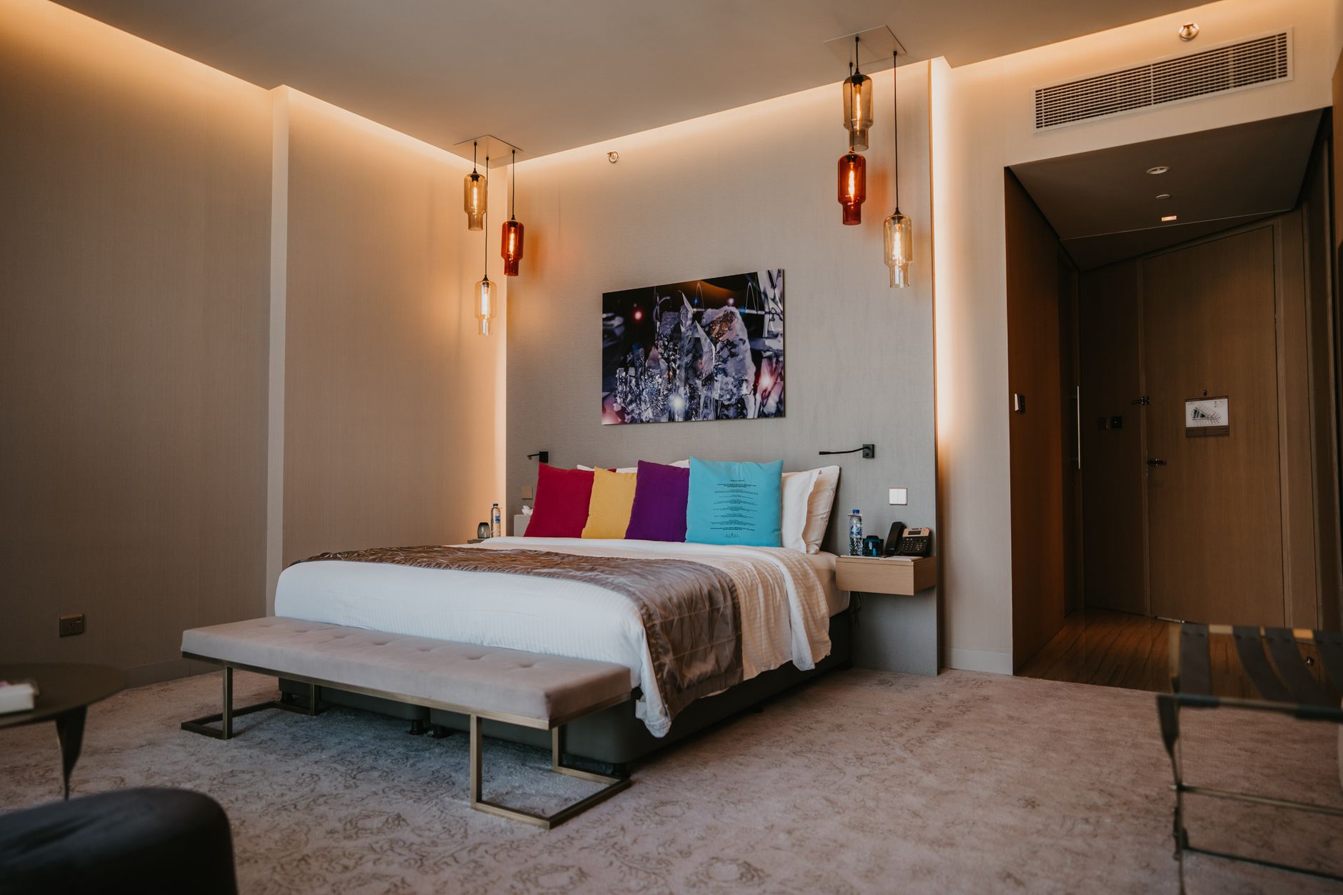 Cozy hotel room in Istanbul featuring vibrant pillows, soft lighting, and modern decor.