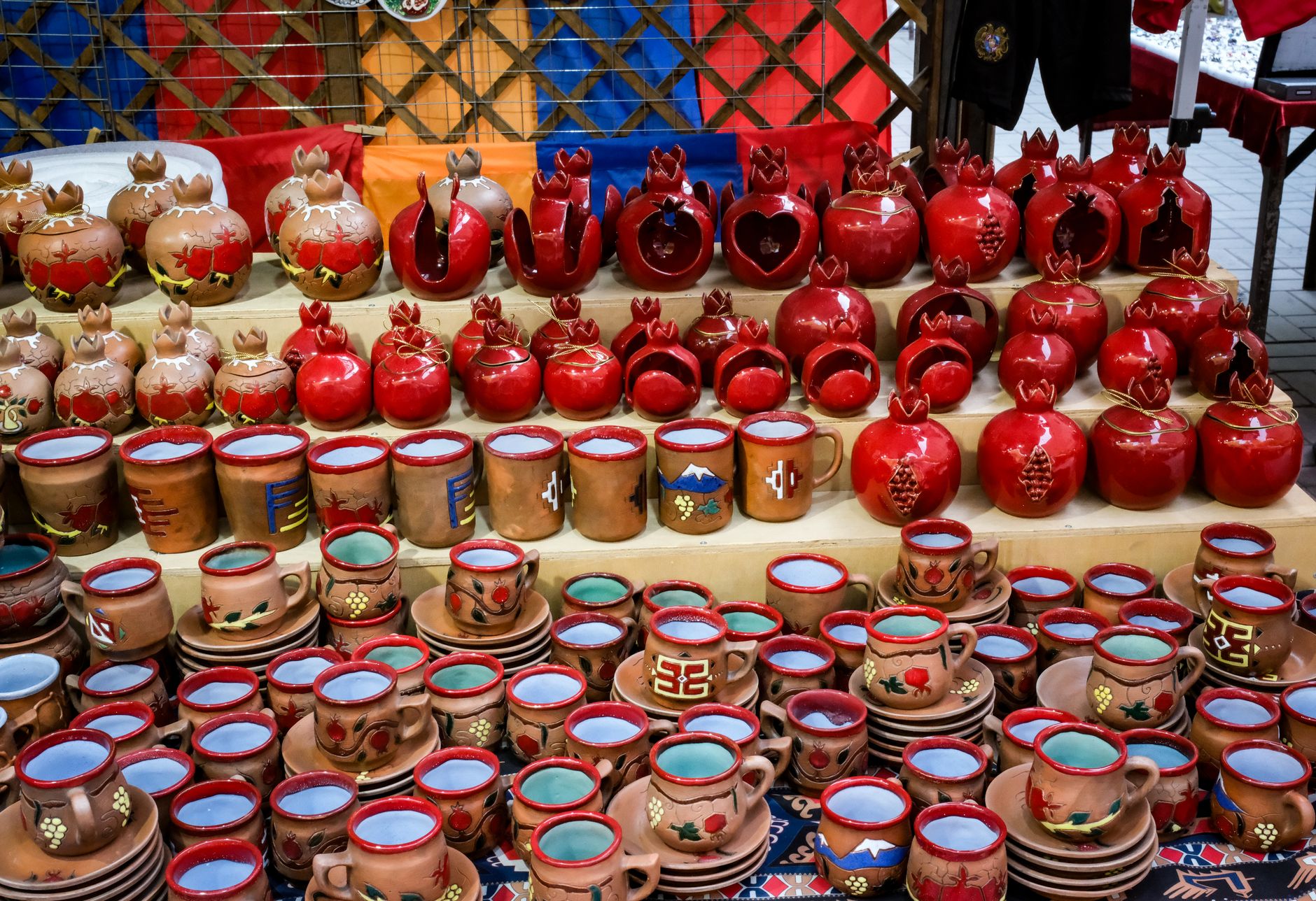 Vibrant display of handcrafted pottery with pomegranates, showcasing unique designs and colors.