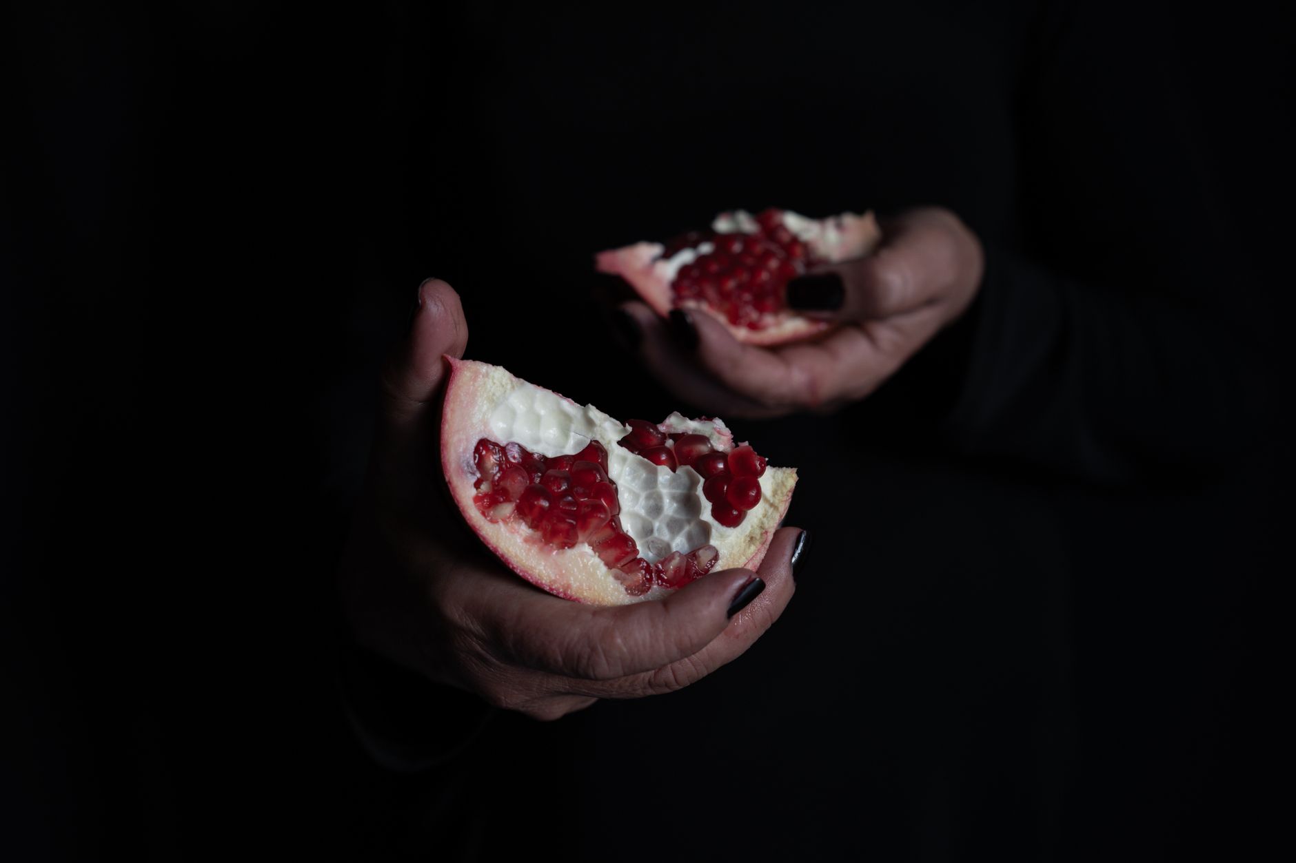 Close-up of hands holding split pomegranate showing ripe seeds, ideal for syrup.