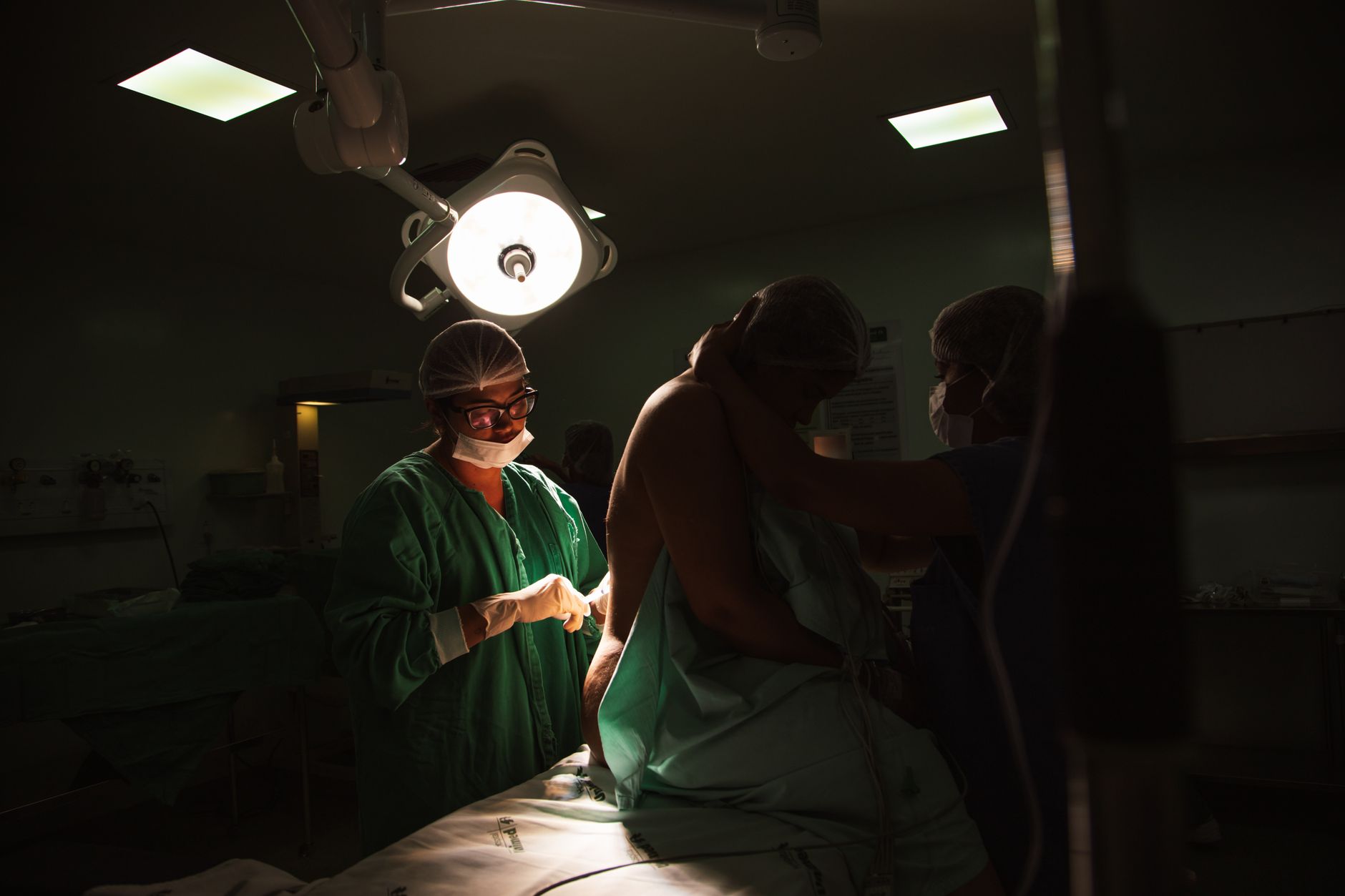 Patient in compression garment on table, assisted by medical staff in surgery room.