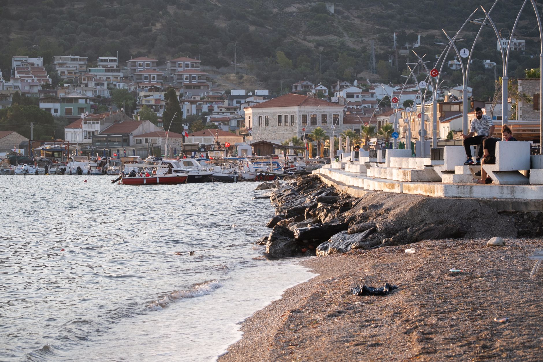 A serene seaside promenade with boats and hills in the background, perfect for gentle walks.