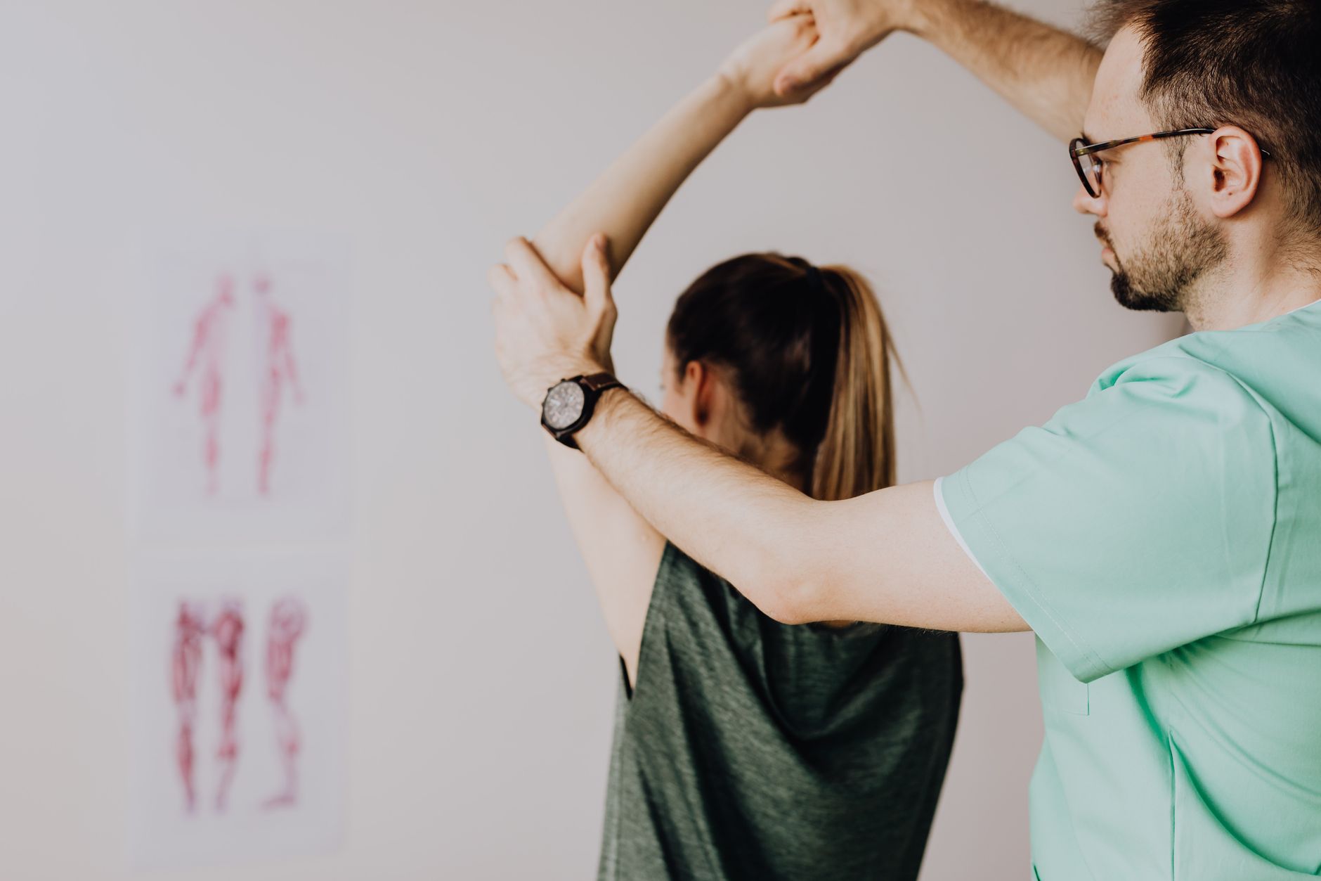 A physiotherapist helps a post-surgery patient with arm exercises in a modern rehab gym.