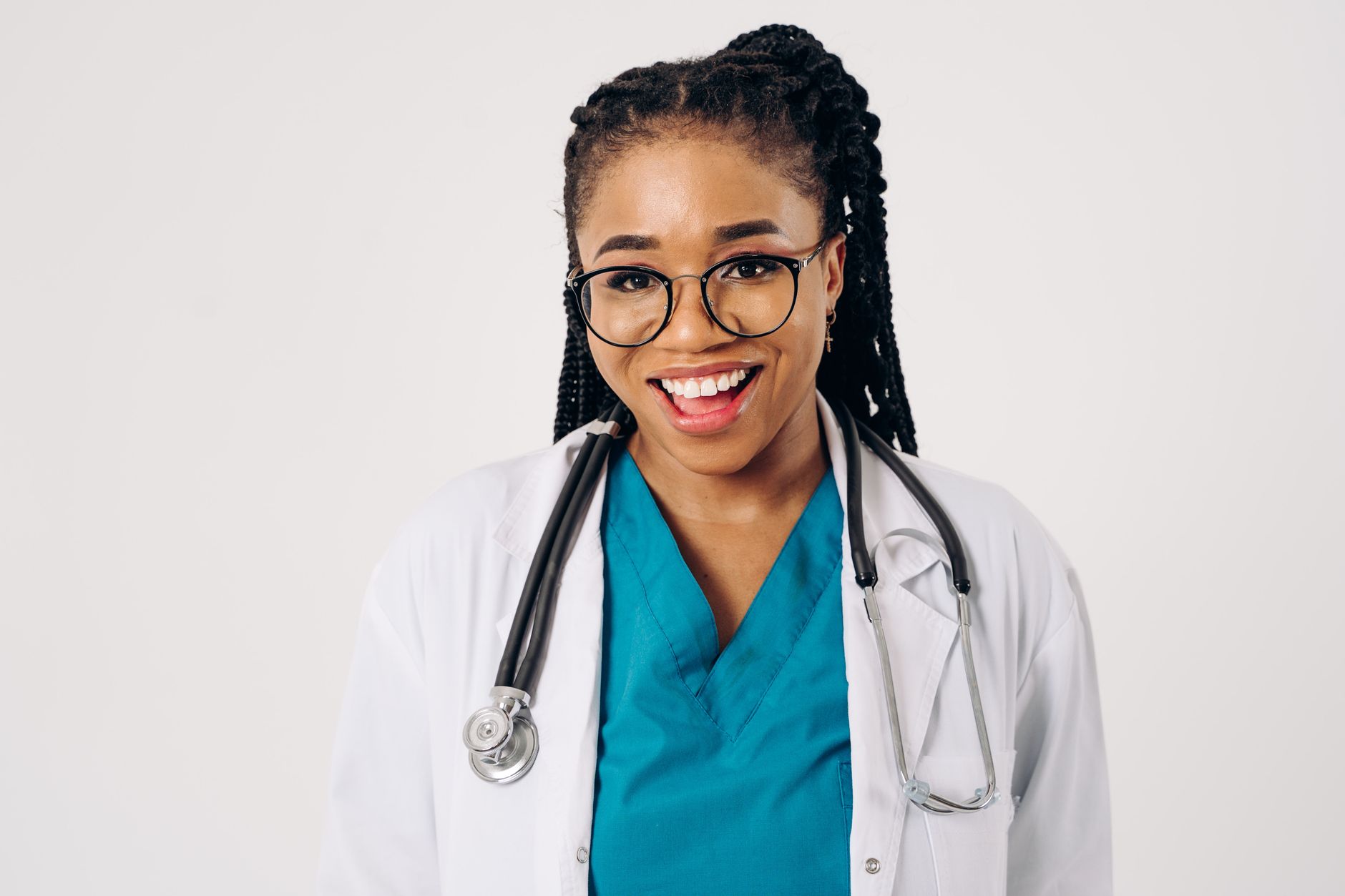 A smiling female doctor in a white coat and stethoscope, ready for telehealth consultations, showcasing patient-first care.