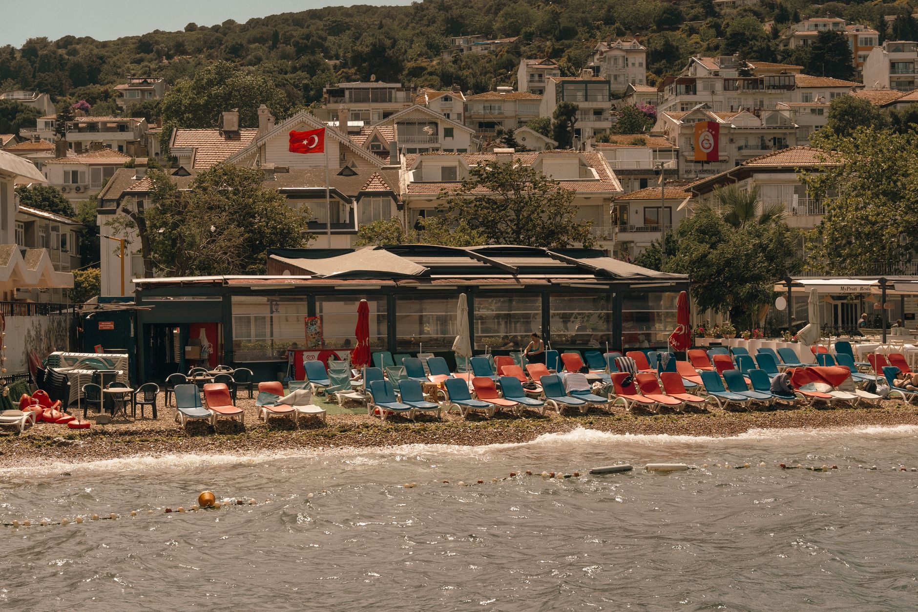A vibrant beach club in Turkey featuring colorful sunbeds and umbrellas by the water's edge.