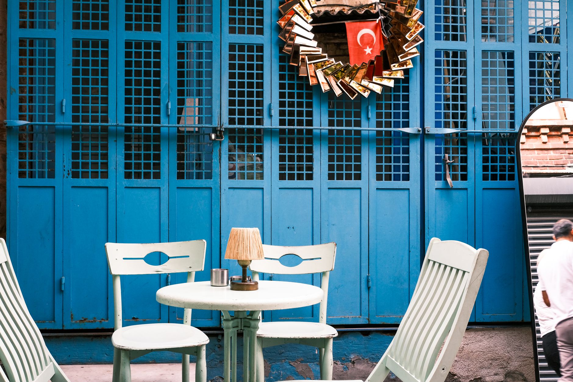 Mavi duvarlı ve küçük masalı bir Türk kahvehanesinin açık hava oturma alanı.