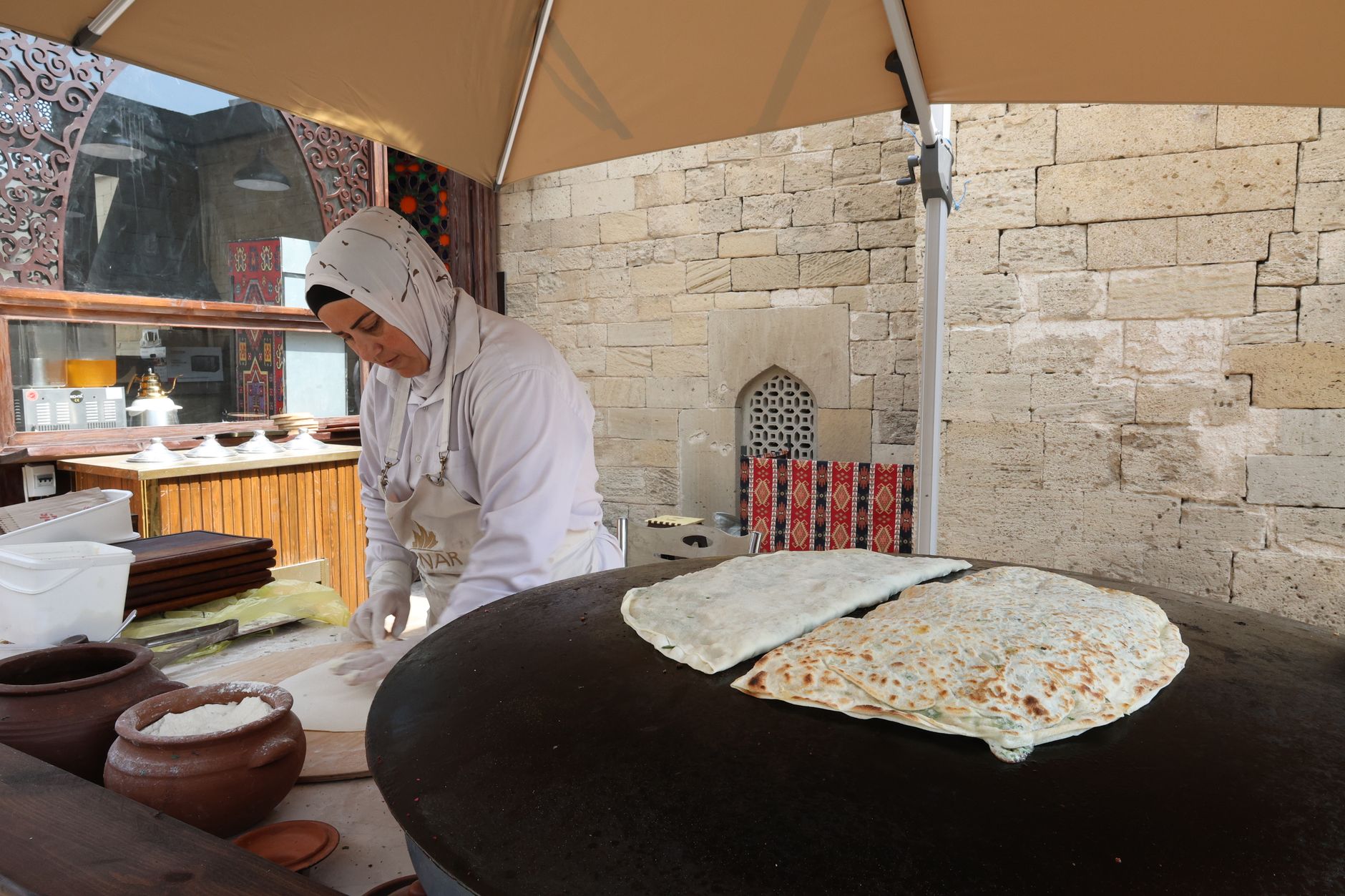 一位女士在户外咖啡馆制作土耳其煎饼，展示当地饮食文化。
