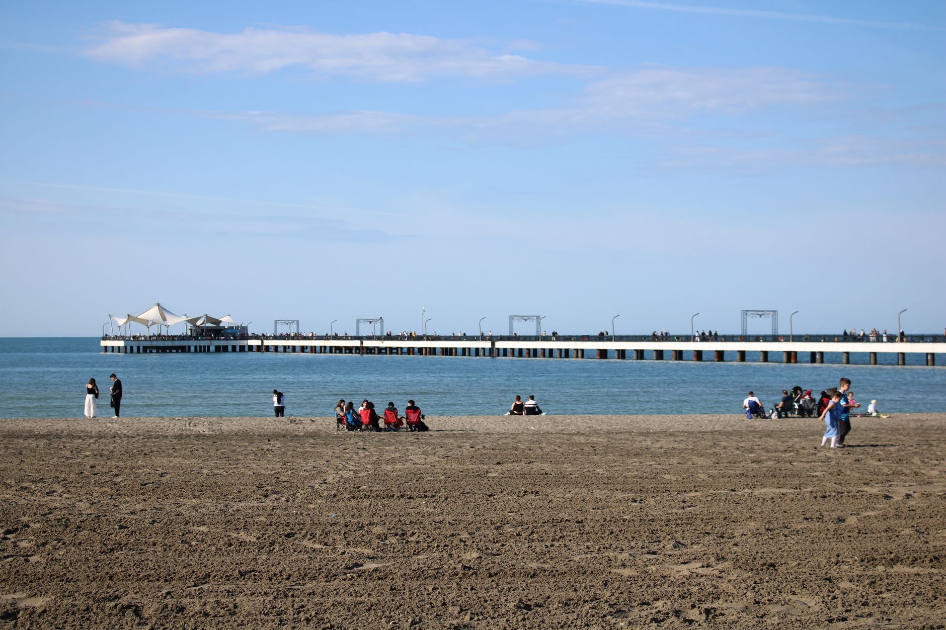 A serene beach in Samsun with people relaxing and a pier in the background.