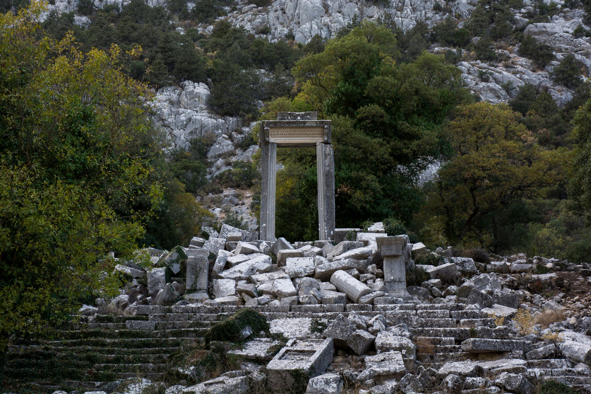 Pisidia Antiokheia'sındaki tiyatro ve tapınak kalıntılarının doğayla çevrili manzarası.