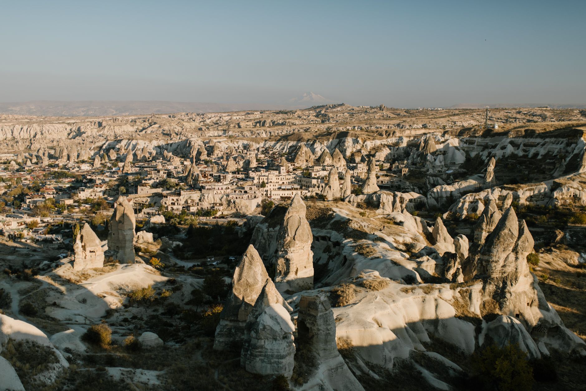 A warm evening light illuminates Cappadocia's fairy chimneys and valley terraces.