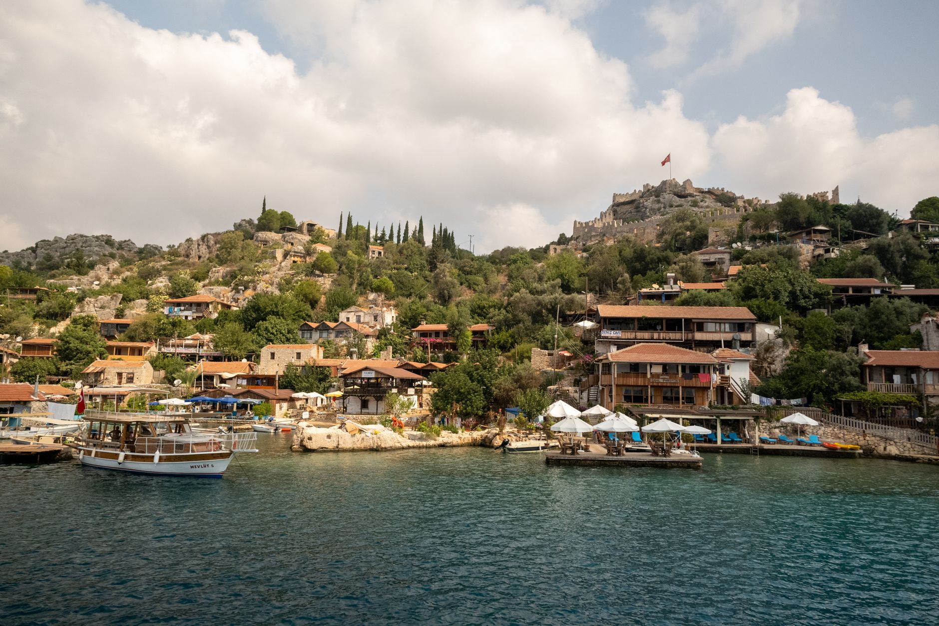 A gulet boat near the sunken ruins of Kekova, Üçağız, with scenic hillside houses.