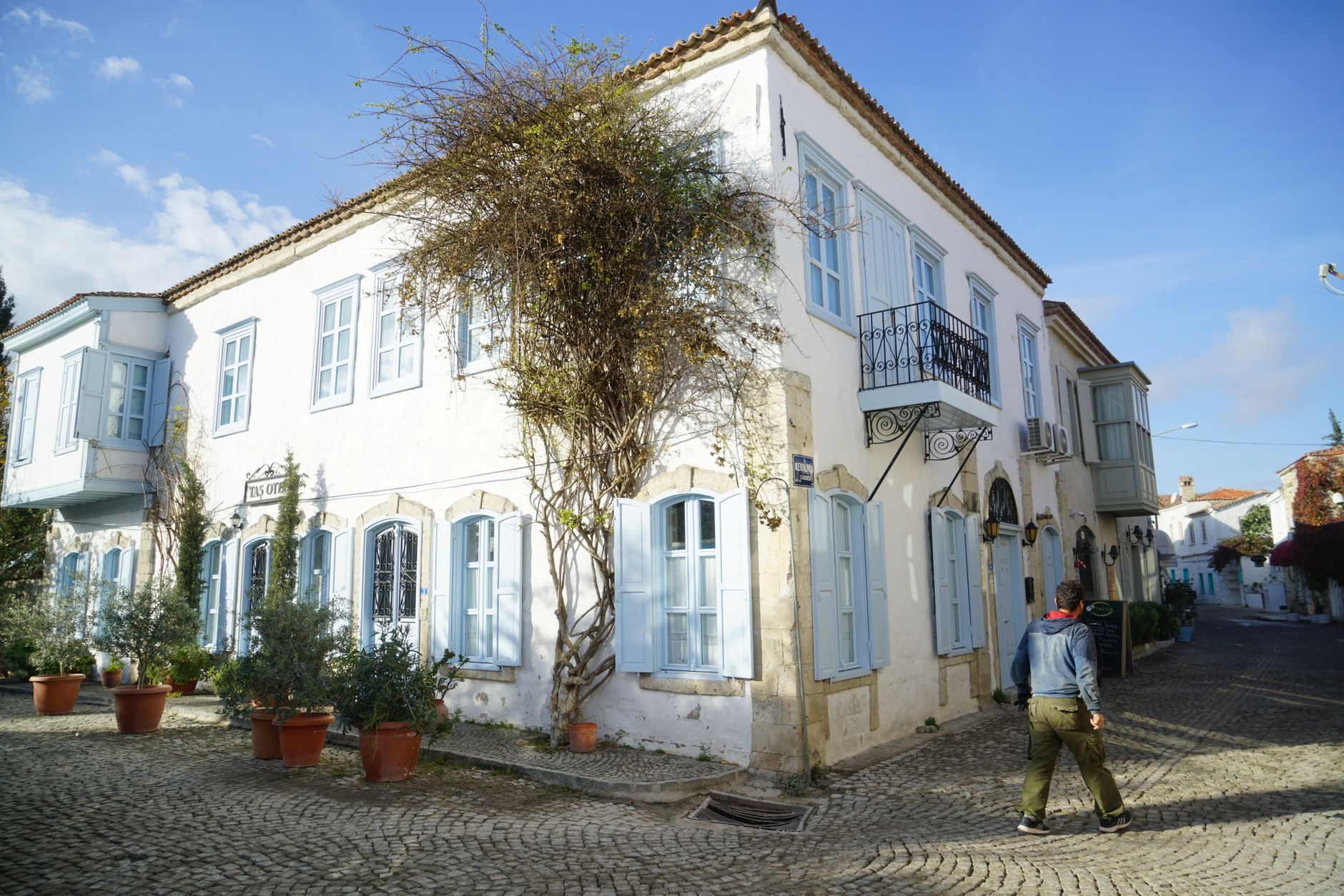 A picturesque whitewashed building with blue shutters and greenery in Kalkan.