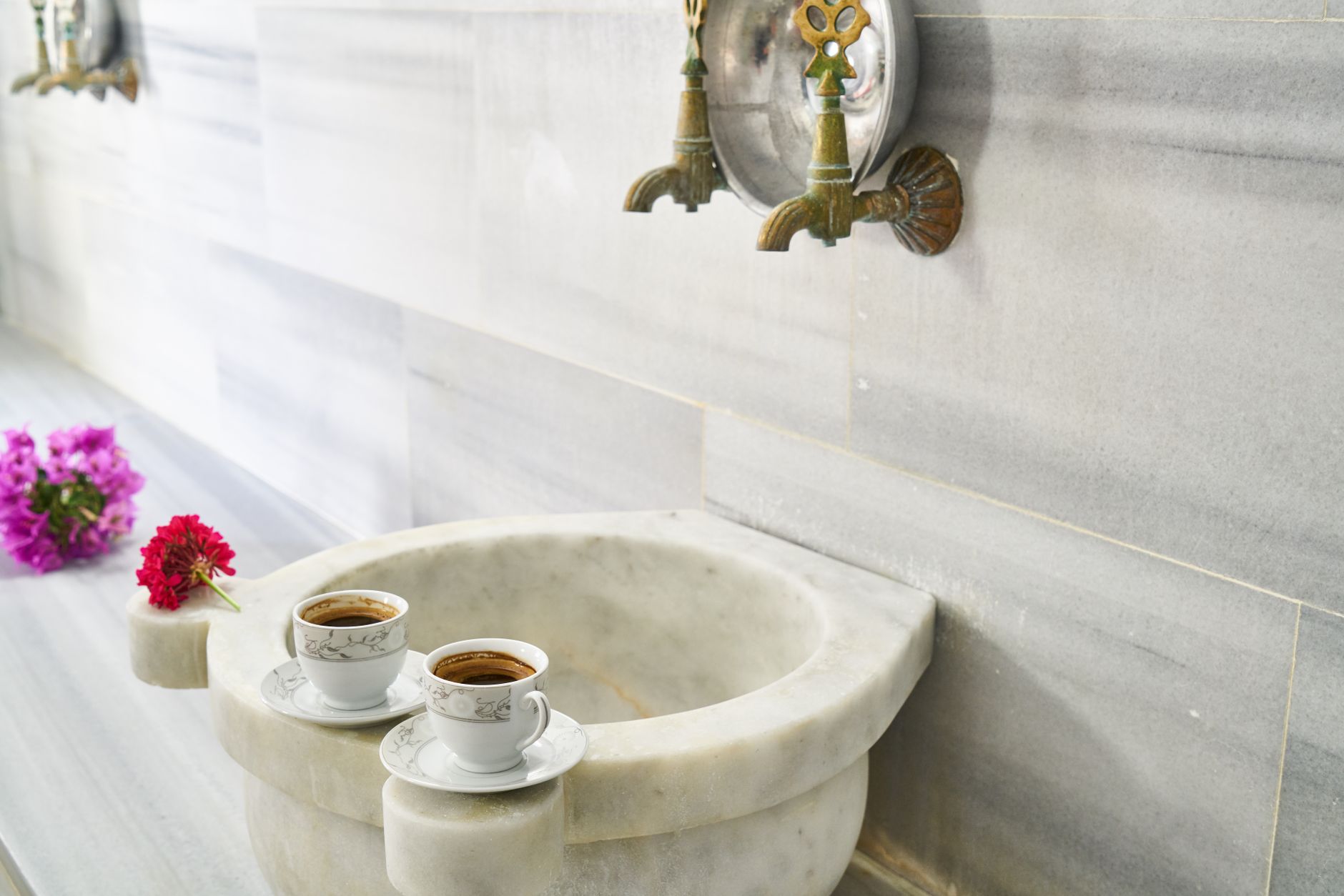 Two cups of coffee on a marble basin with floral accents in a Turkish bath.