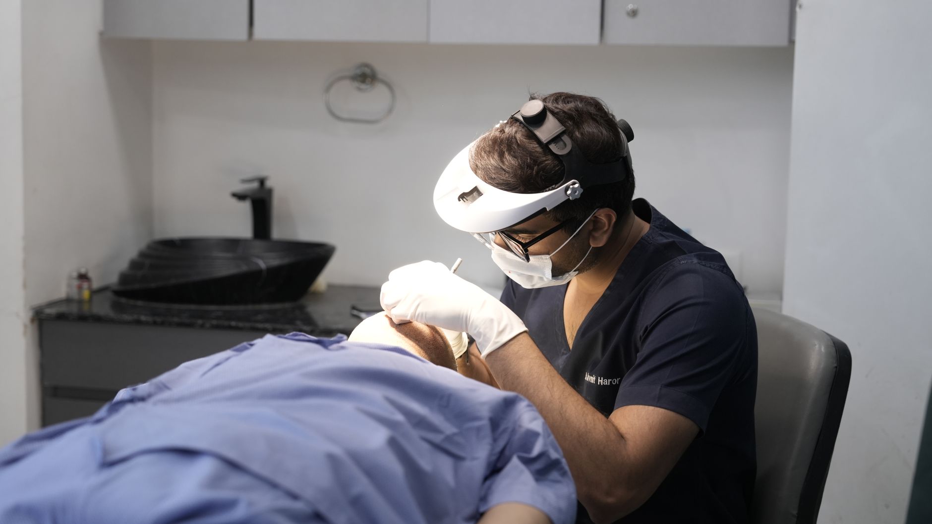 A surgeon conducts Mohs micrographic surgery, carefully working on a patient's scalp.