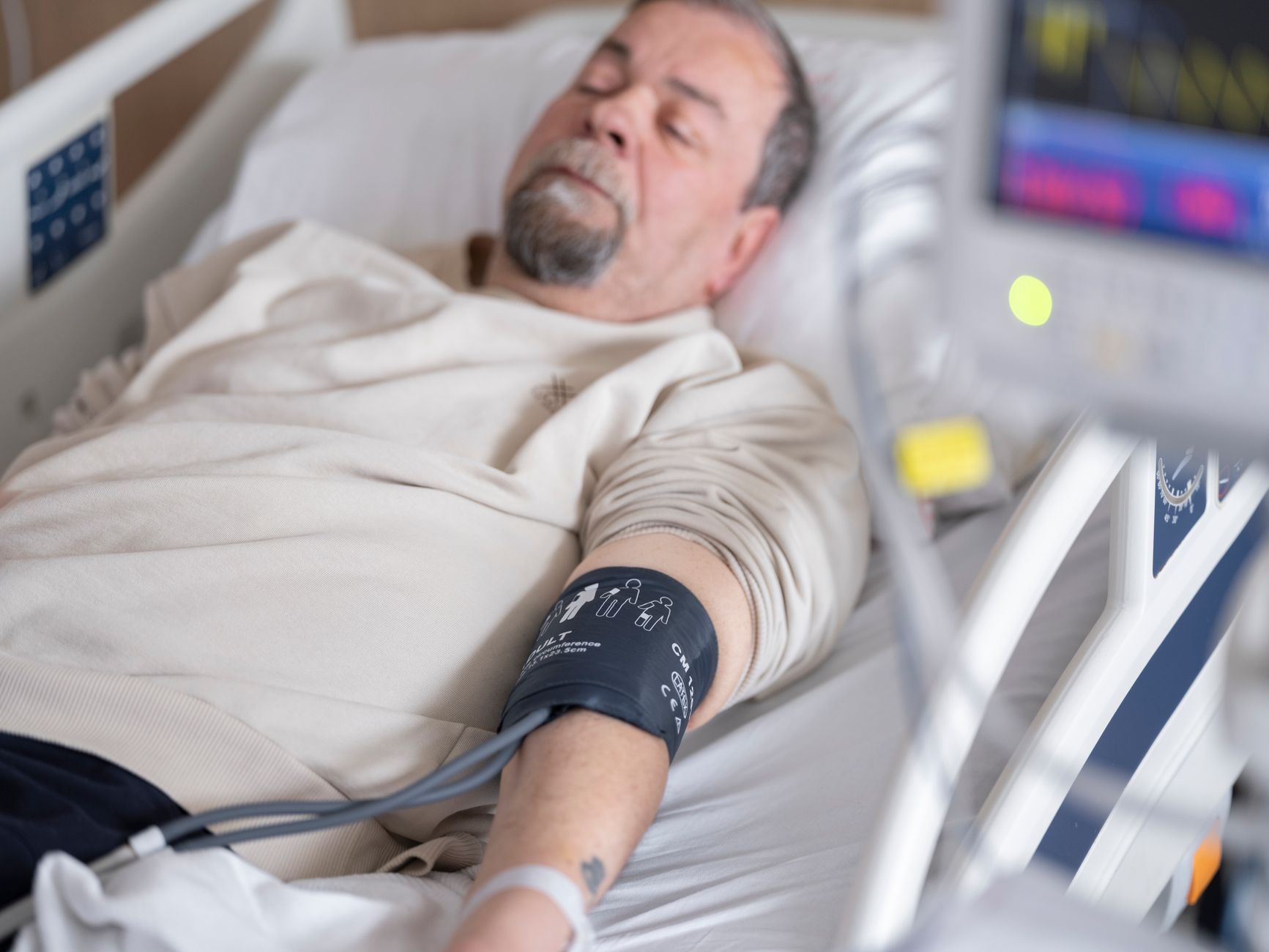 A patient resting in a clinic room with a blood pressure monitor on their arm.