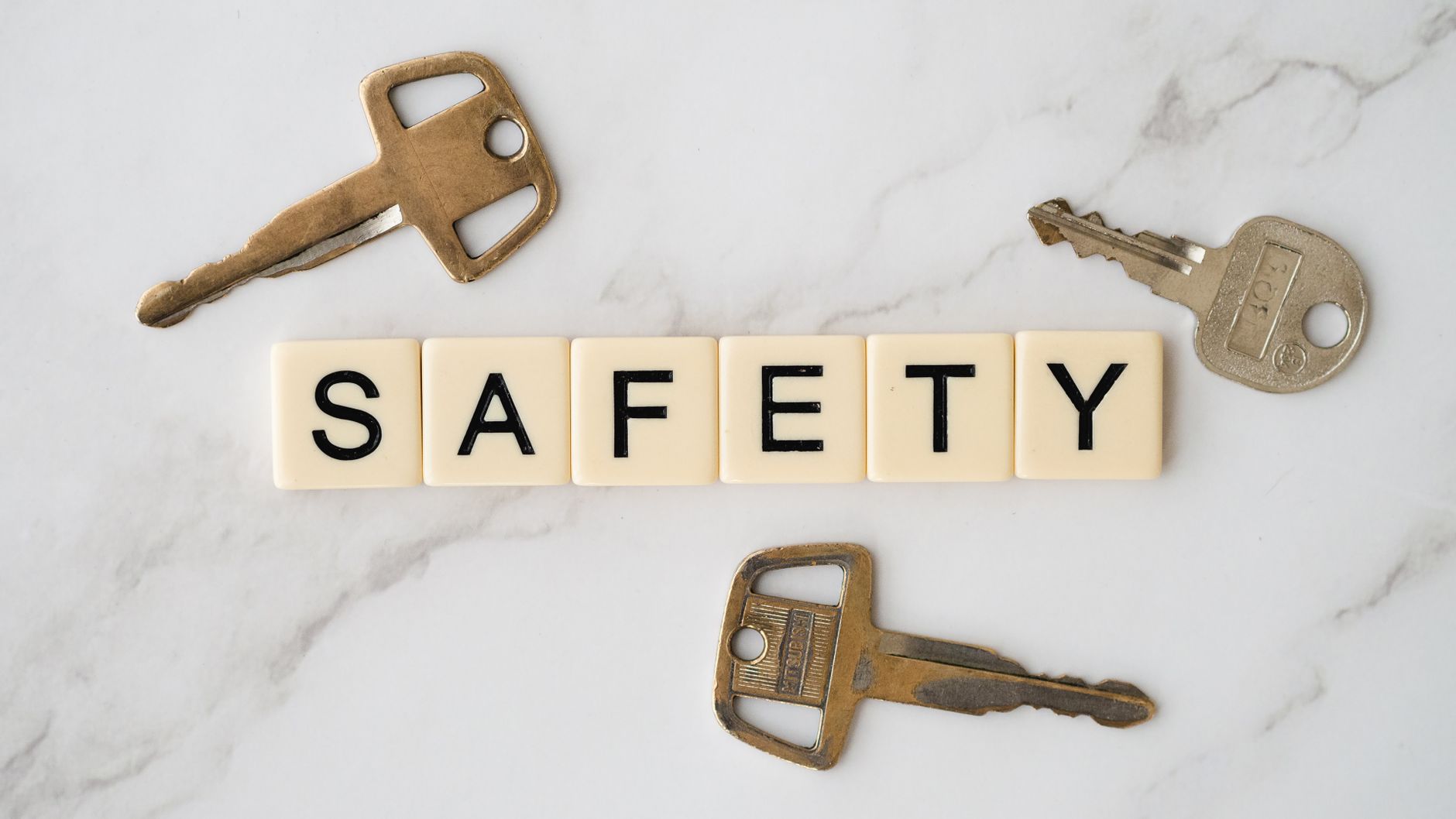Крупный план: ключи разложены вокруг слова 'SAFETY' на мраморном фоне.