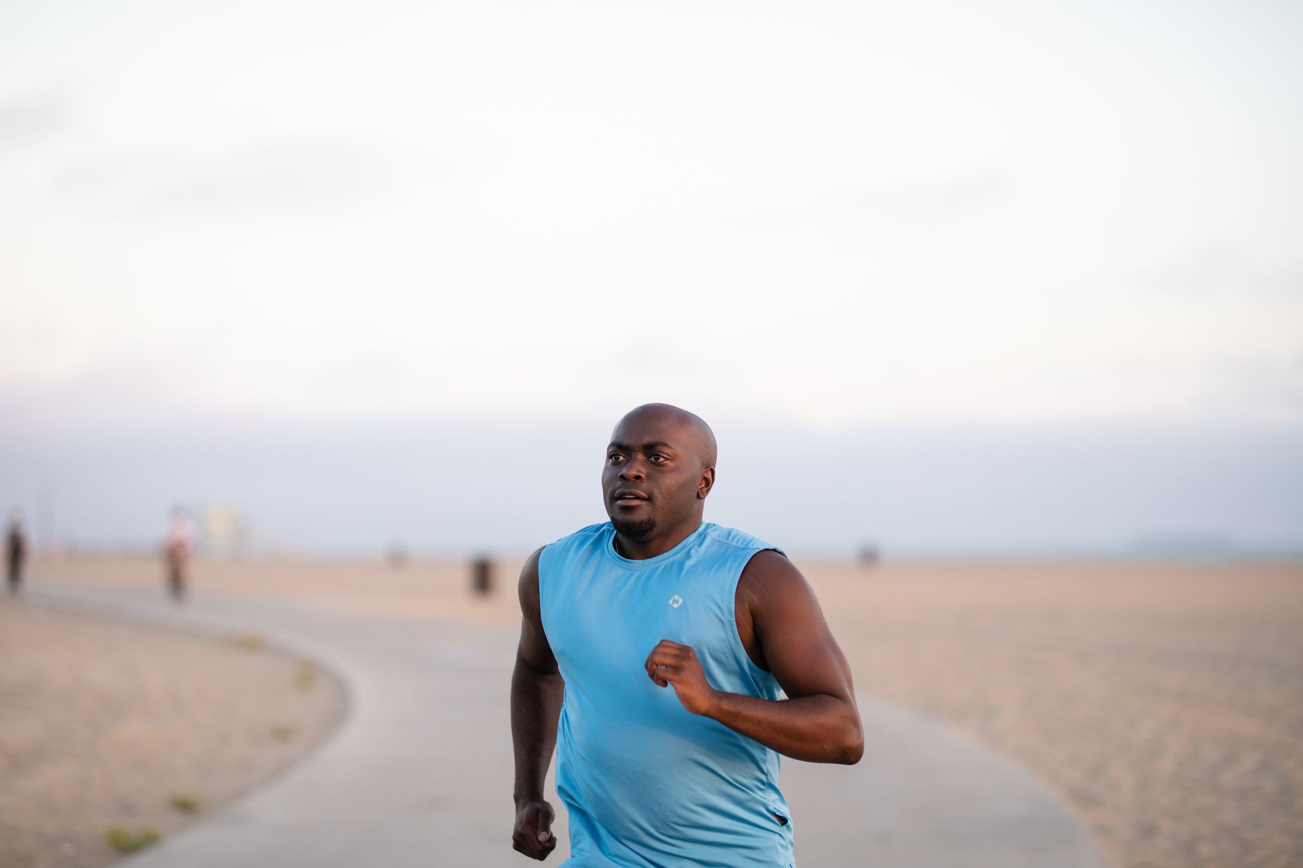 Man jogging on a beachside path during a guided outdoor activity session.