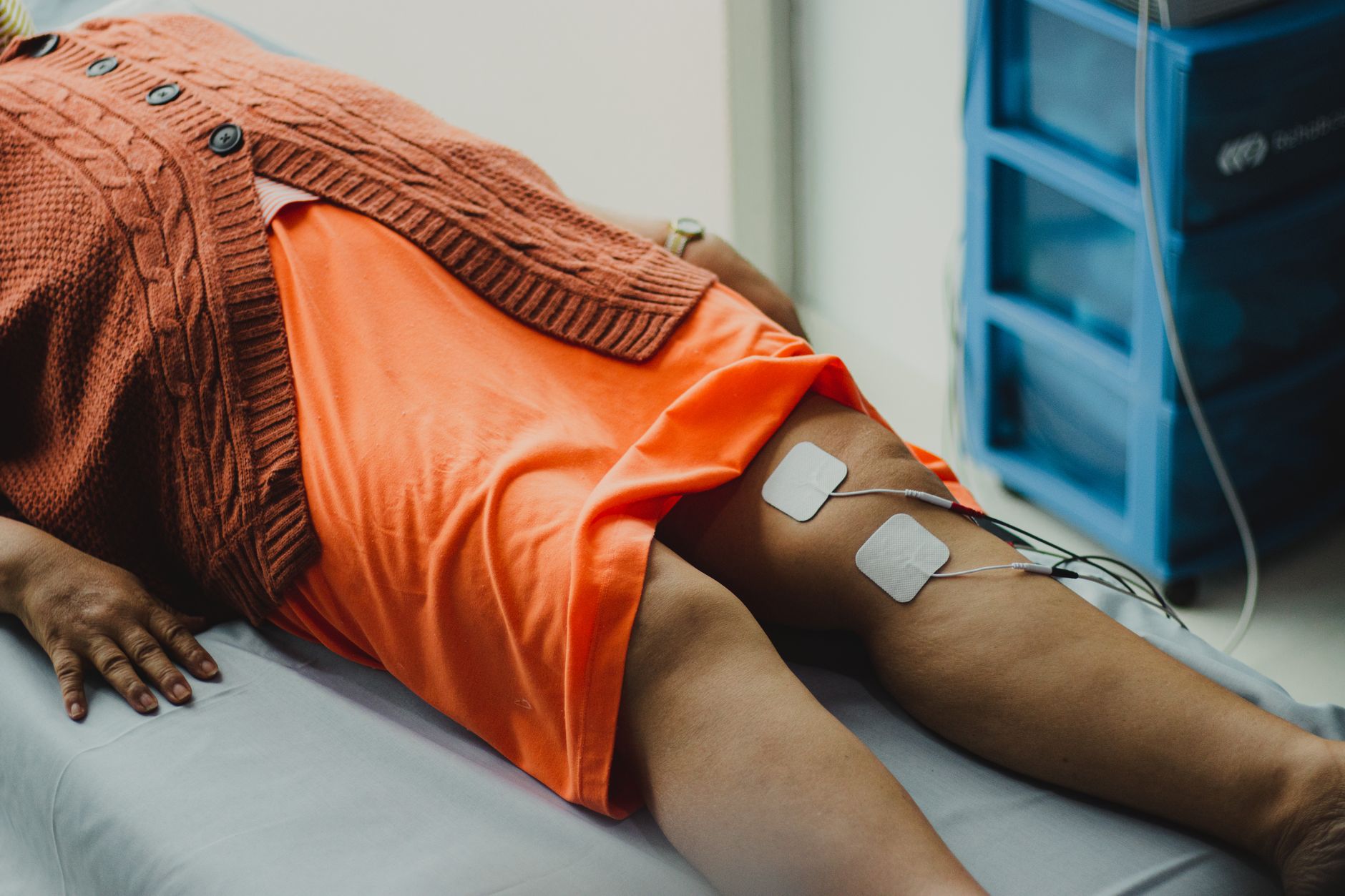 A patient receiving electrotherapy on their knee during physiotherapy in a clinical setting.