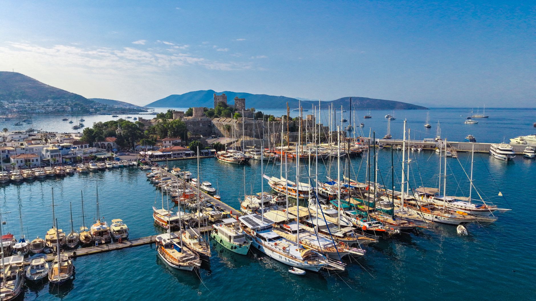 Aerial view of Bodrum marina featuring numerous boats and a historic castle.