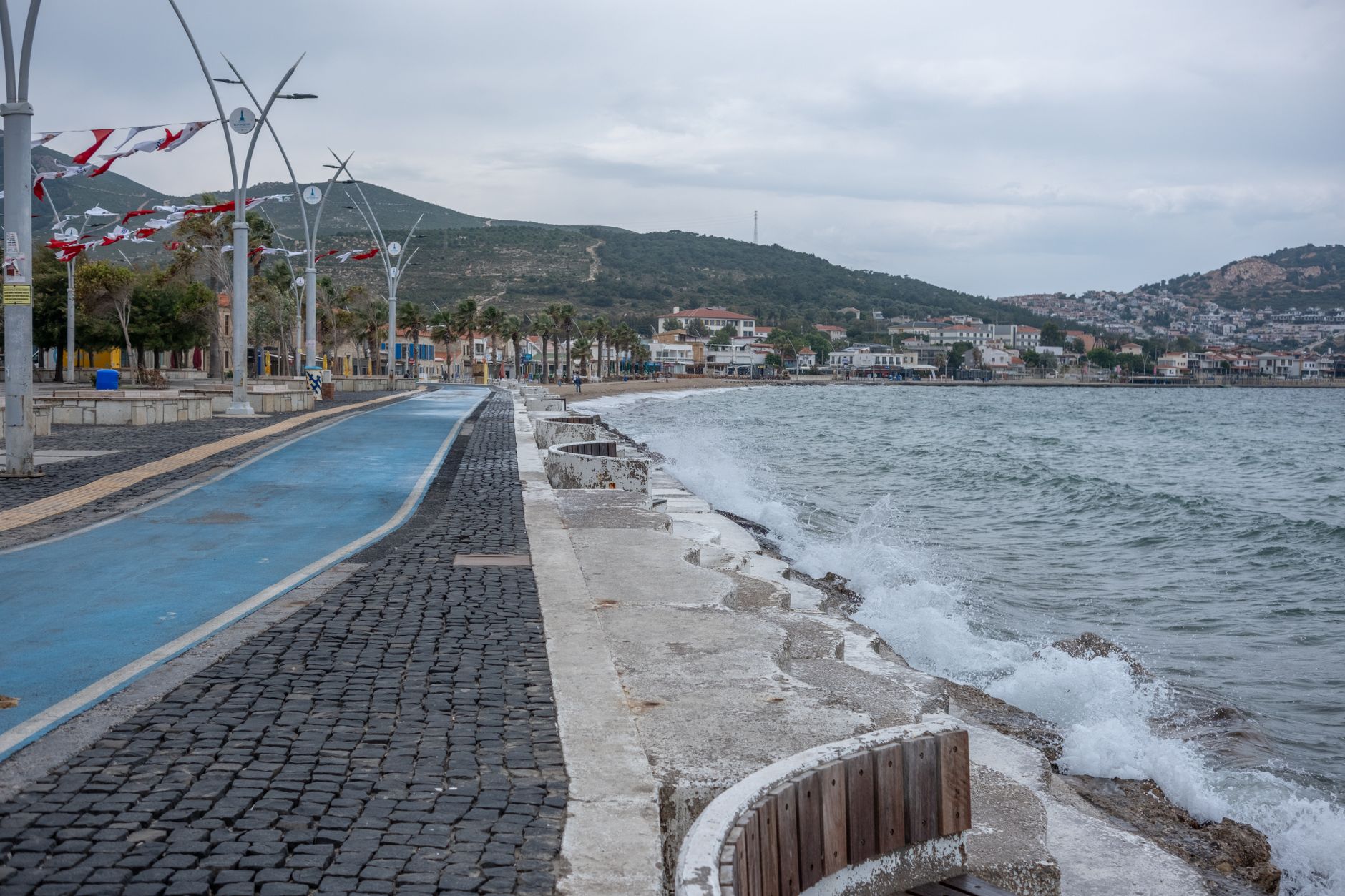 A scenic view of a coastal path in Antalya, with crashing waves and palm trees.