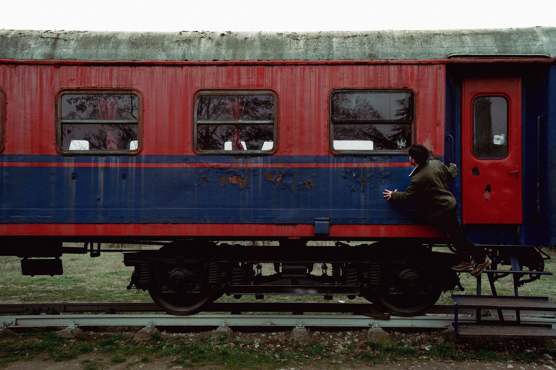 Bir kişi Selçuk istasyonunda rengârenk Whistle Stop Treni'ne binmek üzere tırmanıyor.