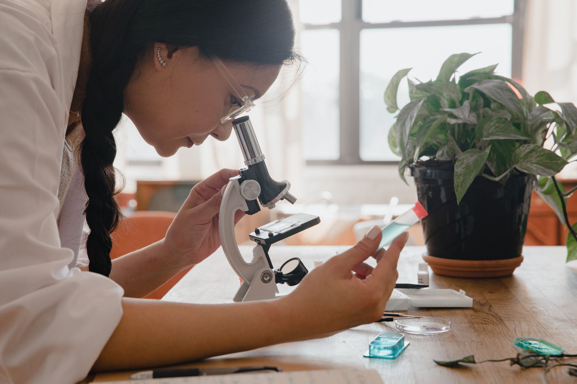 A scientist in a lab coat examines a slide using a microscope in a regenerative medicine lab.