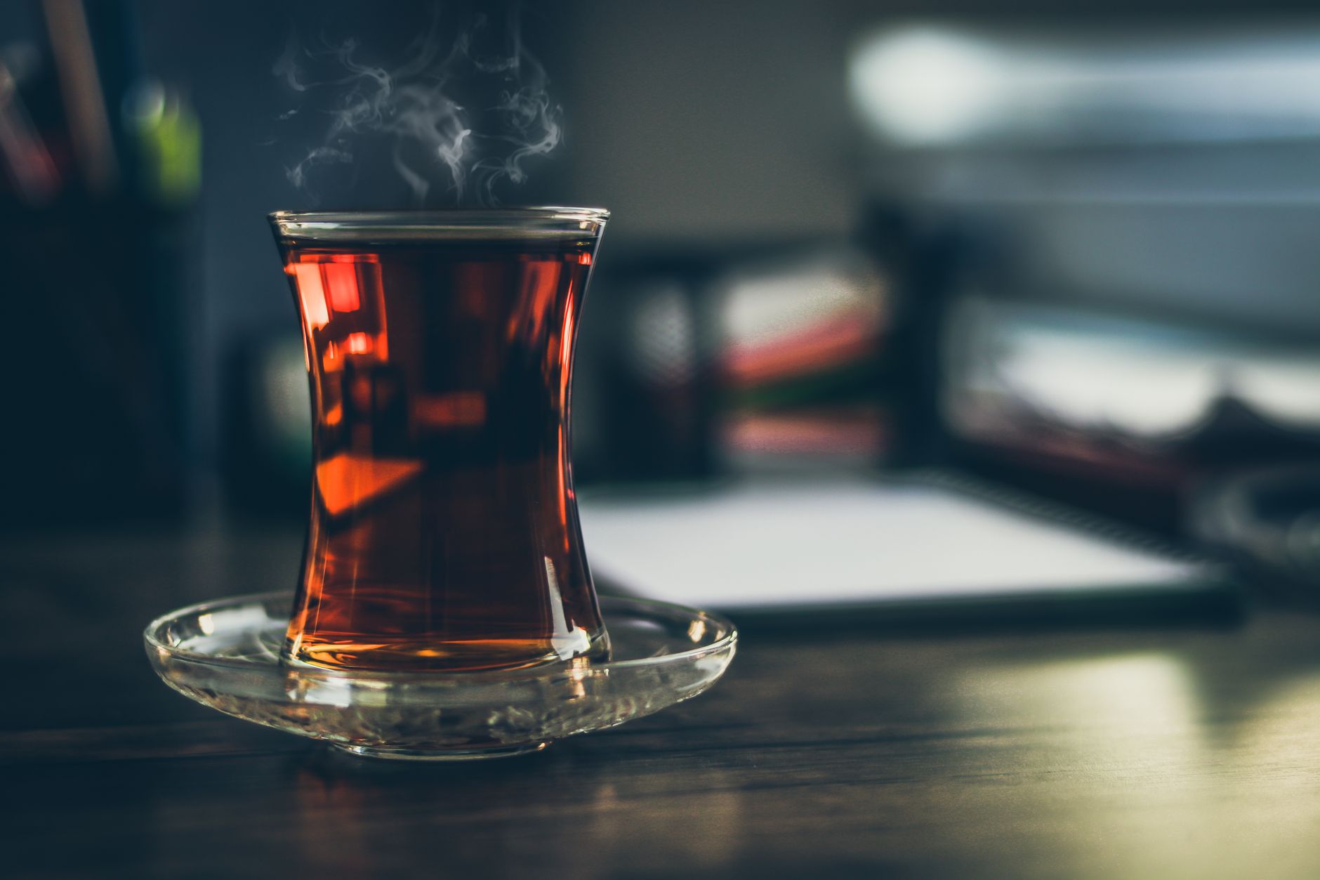 یک فنجان بخارکنان چای ترکی در استکان سنتی روی میز چوبی.