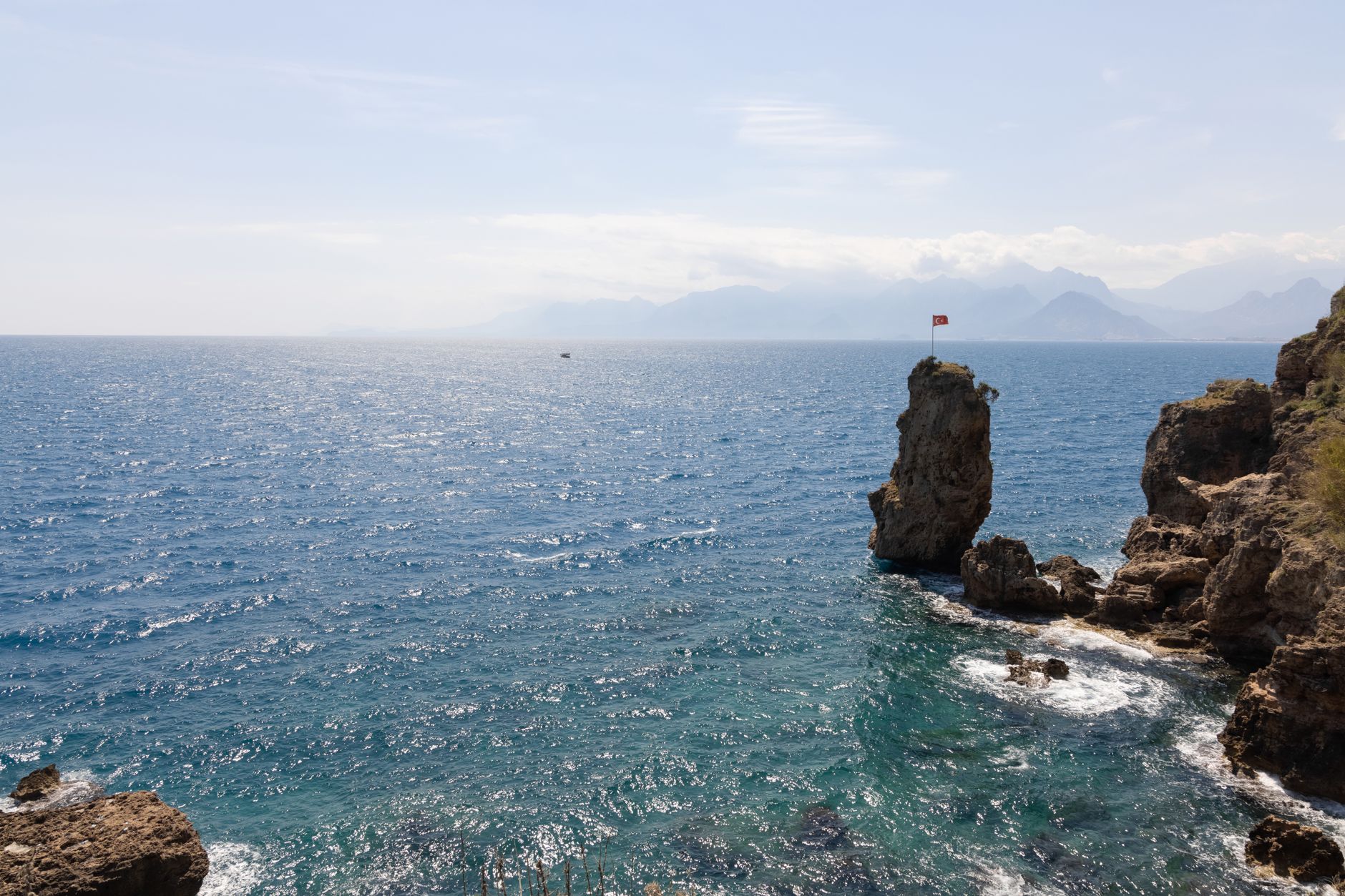 Scenic view of clear blue waters and rocky coastline in Antalya under bright skies.