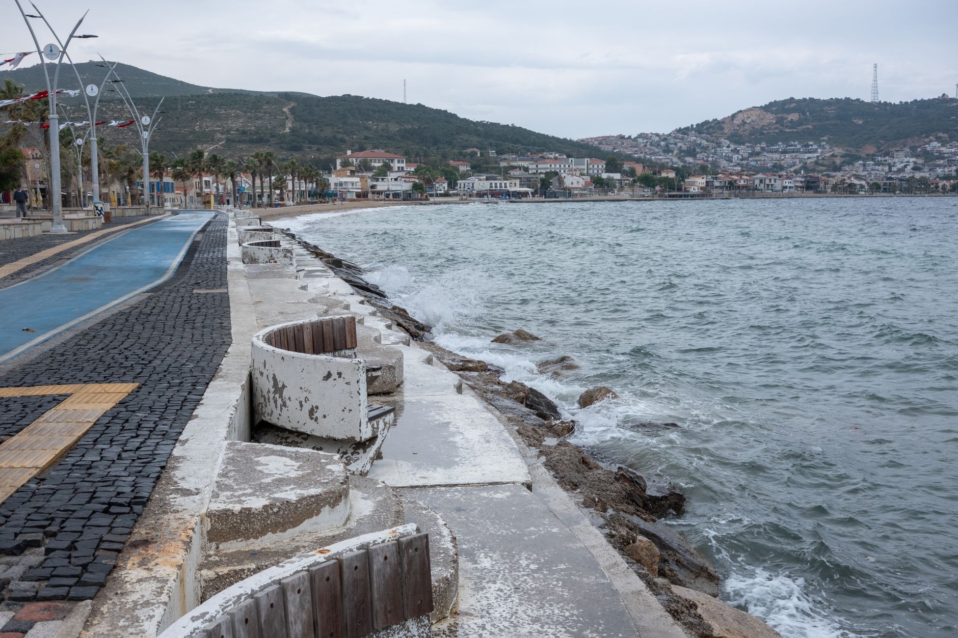 Serene view of the Aegean coastline near Cesme, with gentle waves and a peaceful promenade.