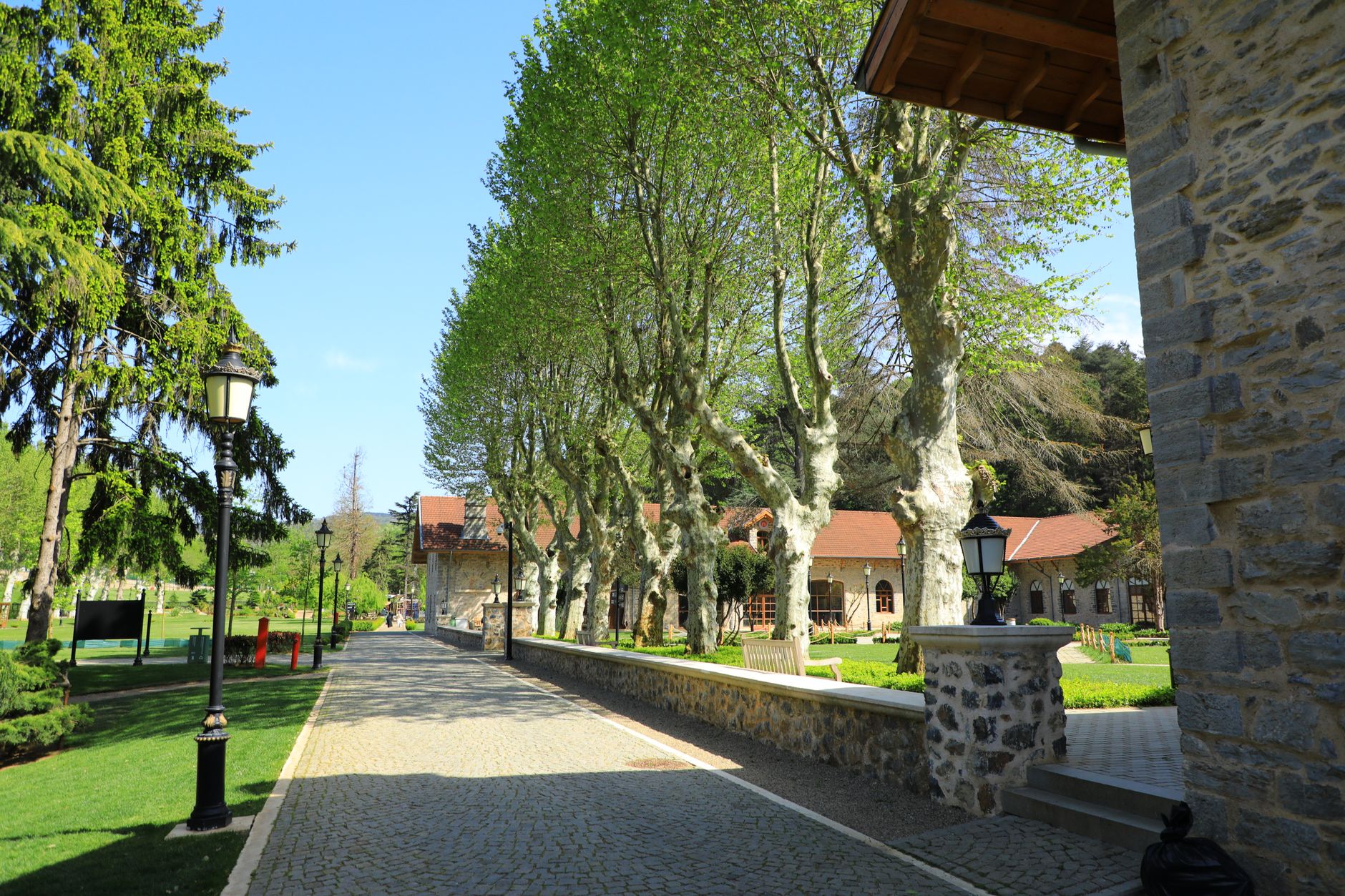 Yalova Termal'de yeşil ağaçlar ve taş binalarla çevrili pitoresk bir patika.