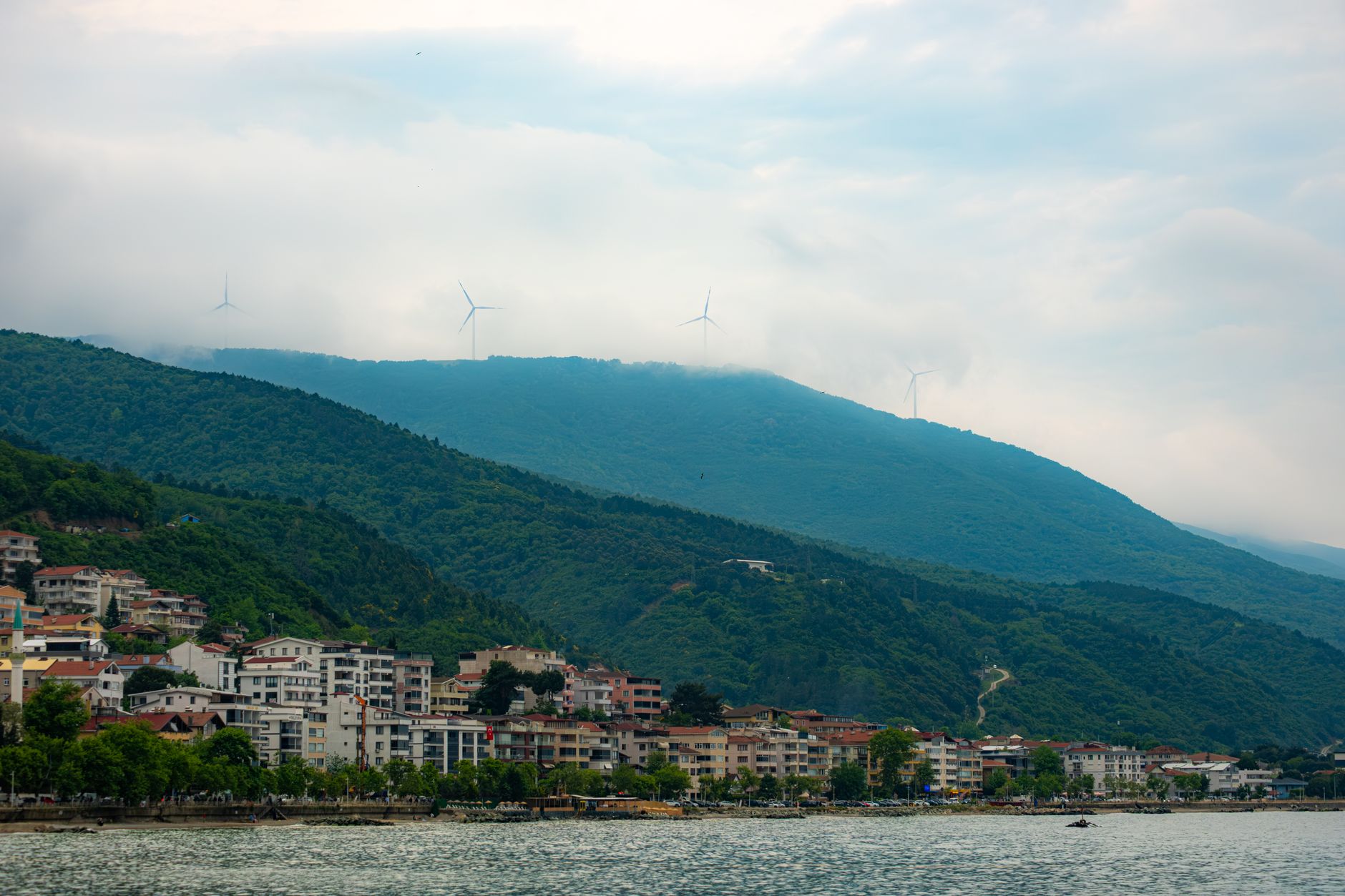 A serene view of Yalova, displaying green hills, cloudy skies, and calm waters along the Marmara coastline.