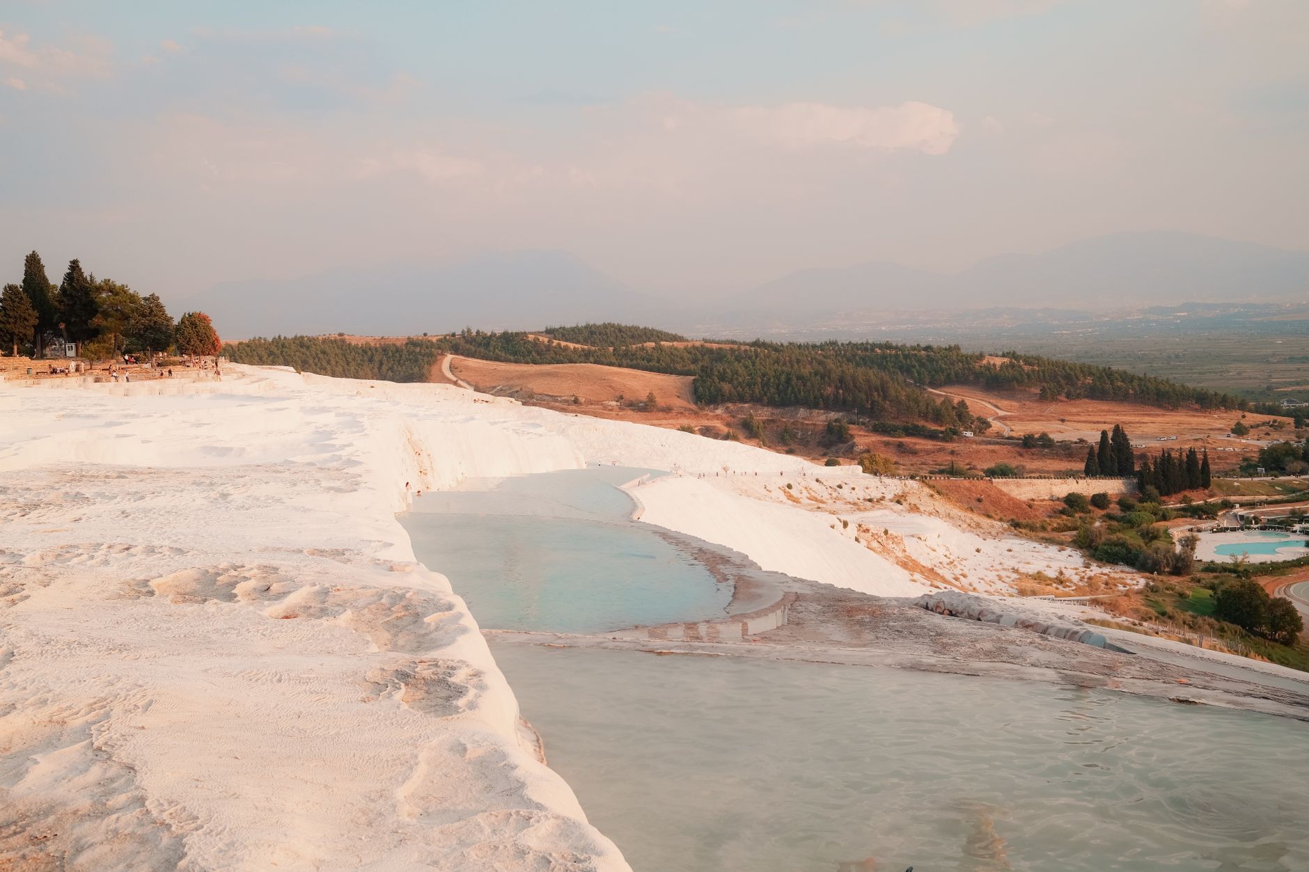 A view of Pamukkale's white terraces and turquoise waters, surrounded by greenery.