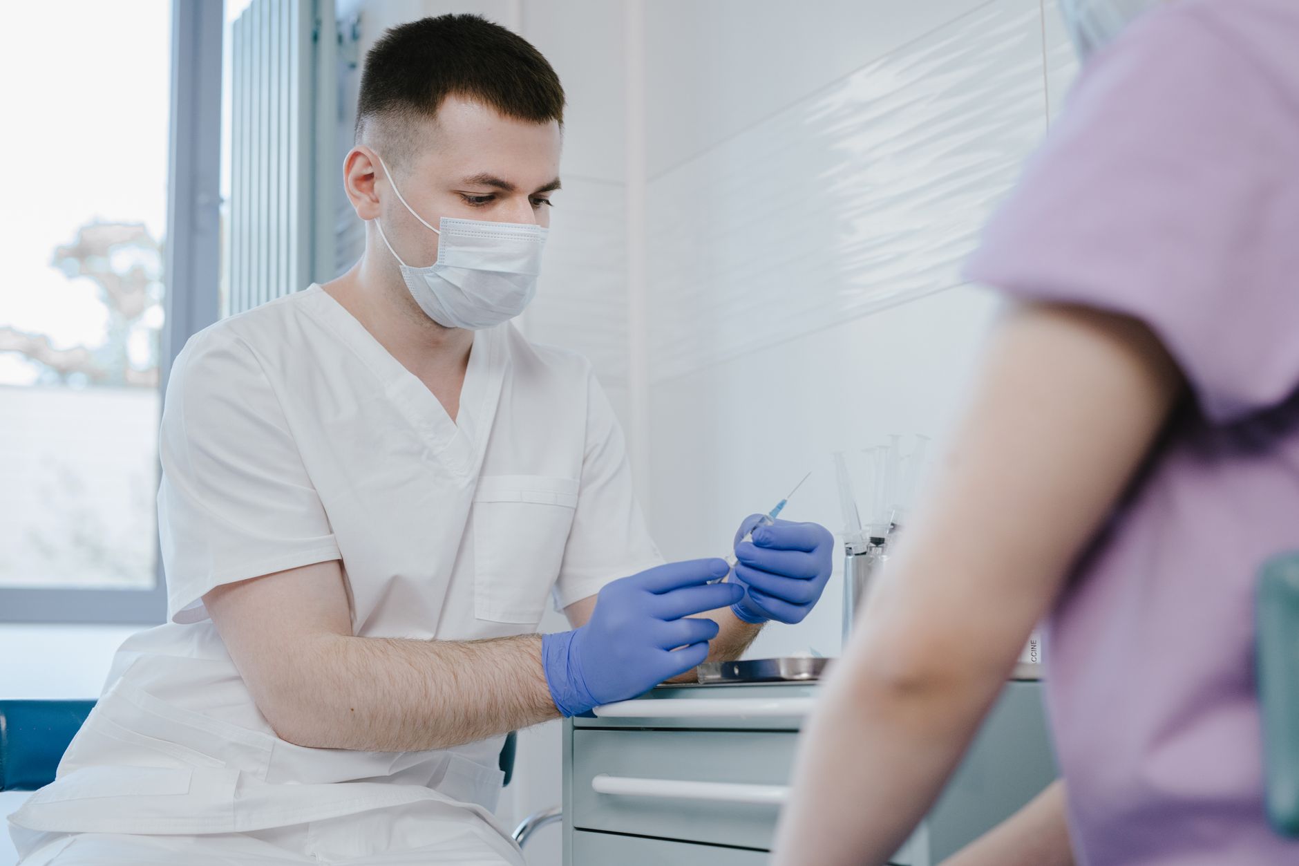 Close-up of a physician preparing a syringe for a biopsy procedure on a patient's neck.