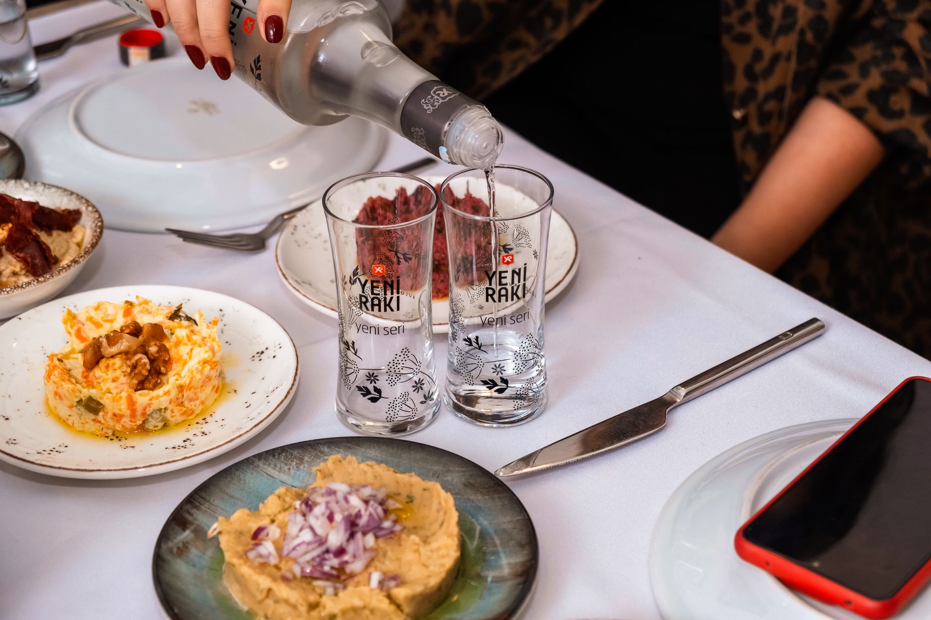 Enjoying traditional Turkish meze dishes alongside Yeni Raki at a dining table.