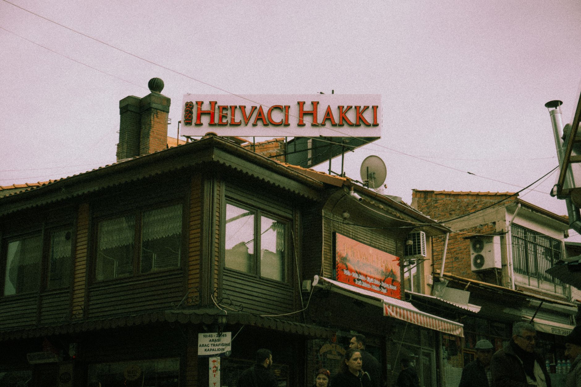 Exterior view of Helvaci Hakki restaurant, bustling with visitors in a charming Istanbul street.