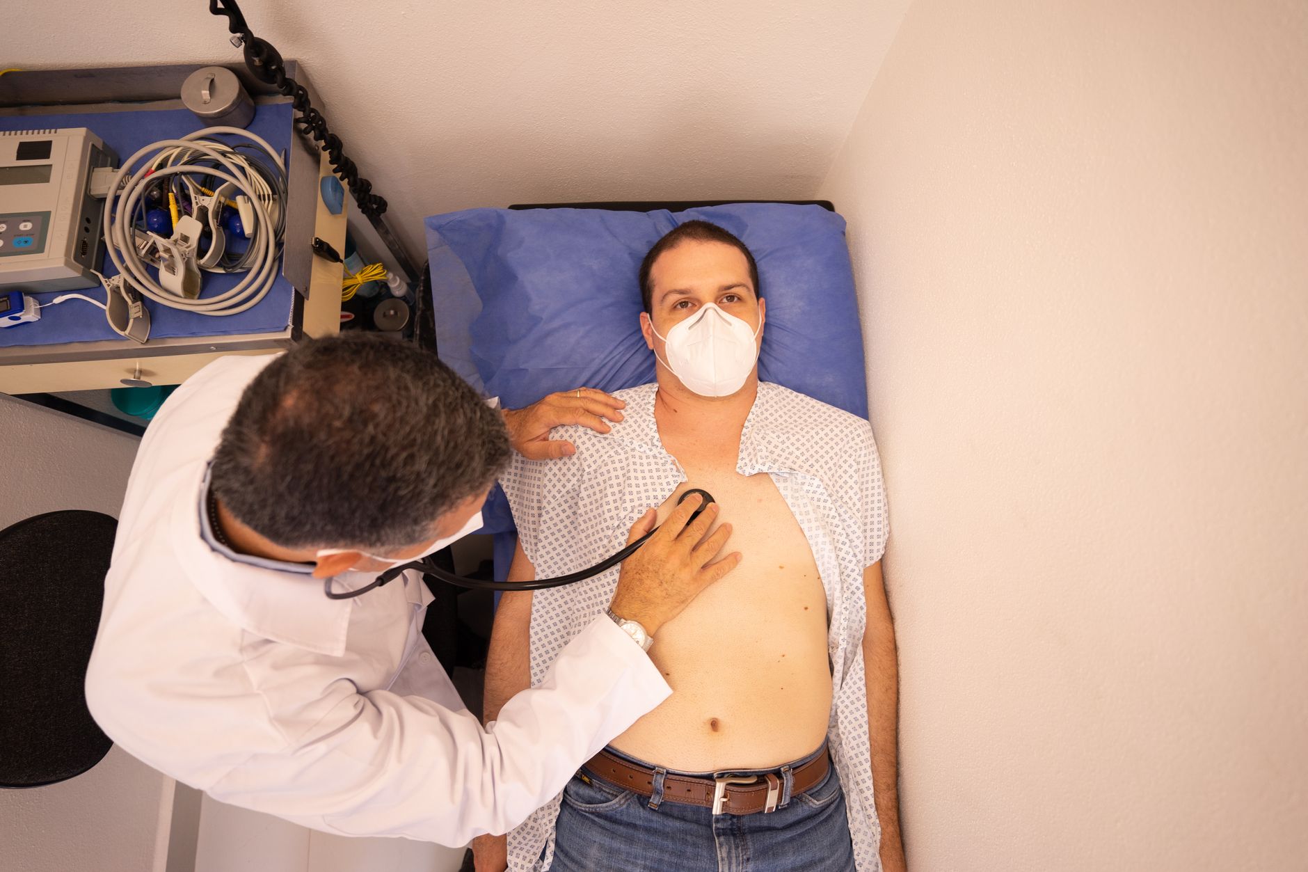 A doctor examines a patient lying on a bed during a liver transplant assessment.