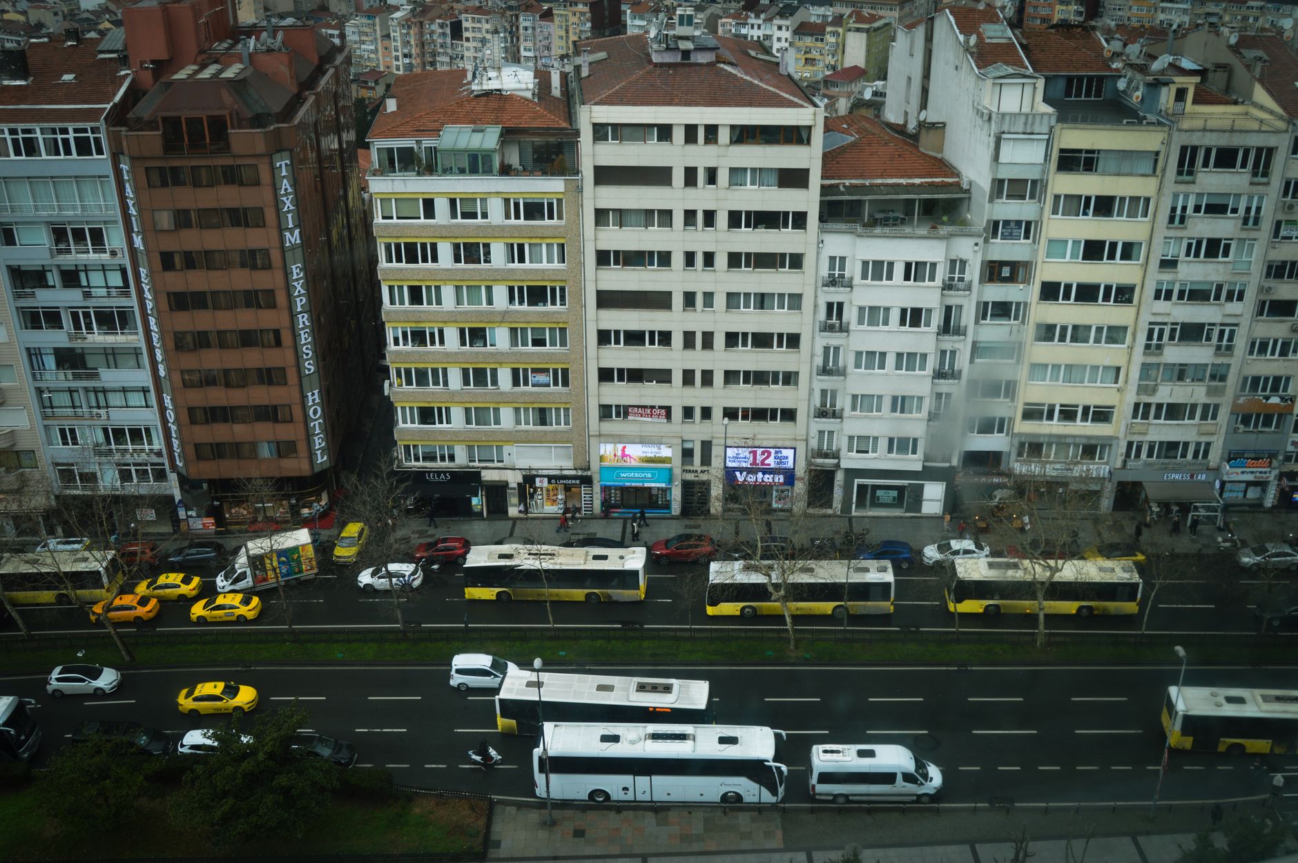 View of Taksim Express Hotel and busy street in Istanbul with buses and taxis.
