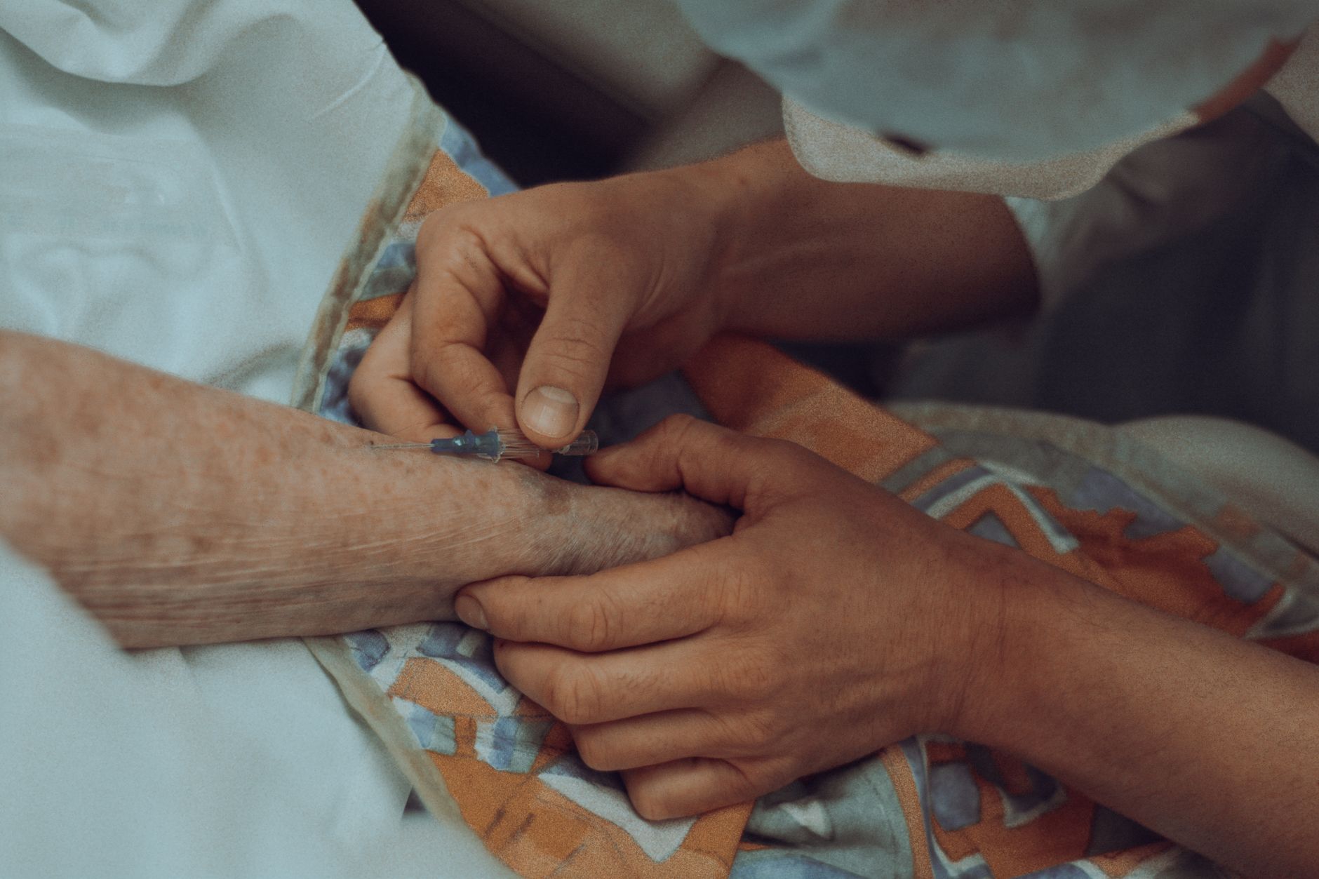 A nurse gently places an IV on a patient's arm in a hospital.