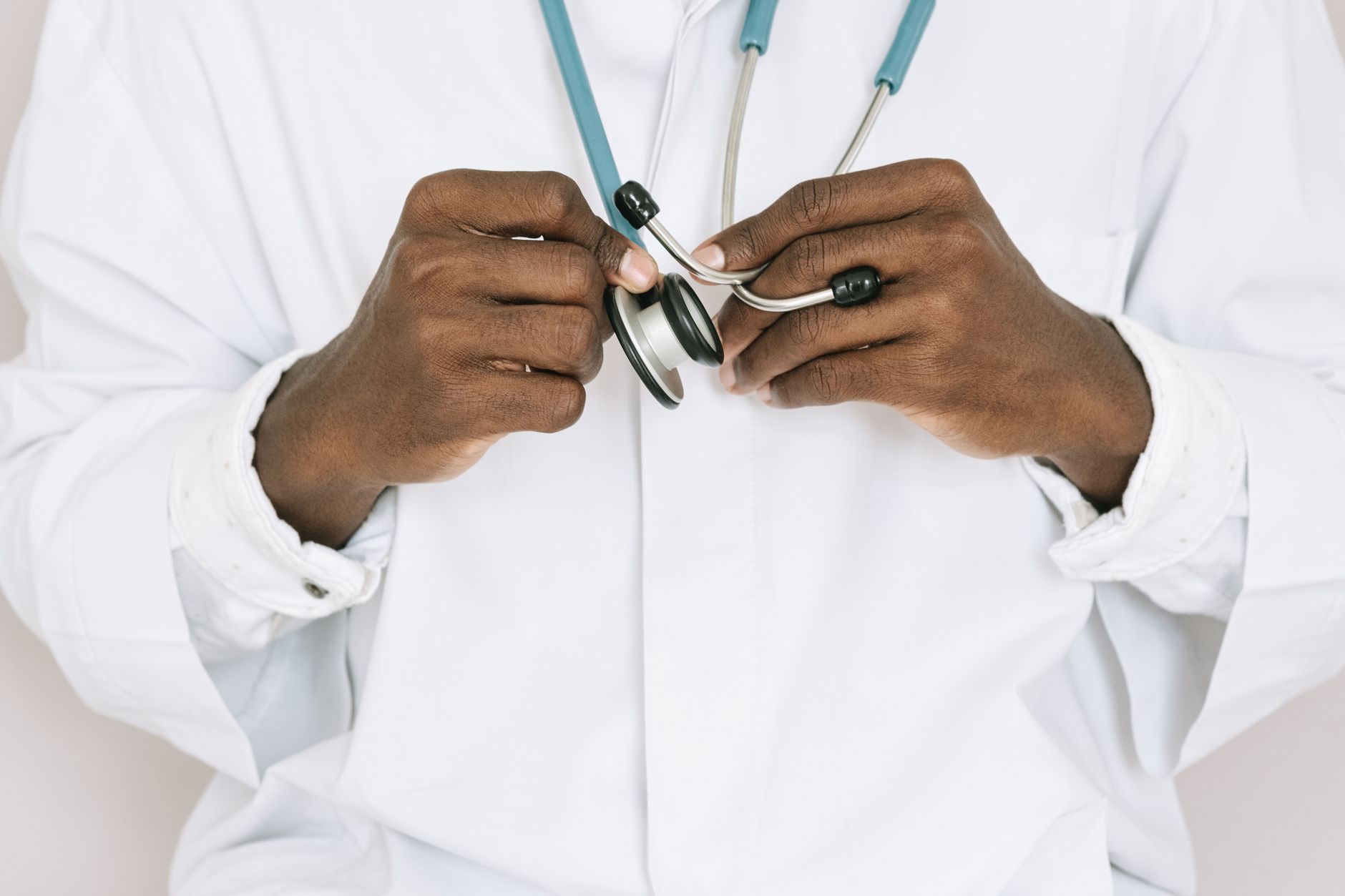 Close-up of a UK GP in white coat holding a stethoscope, symbolizing healthcare collaboration.