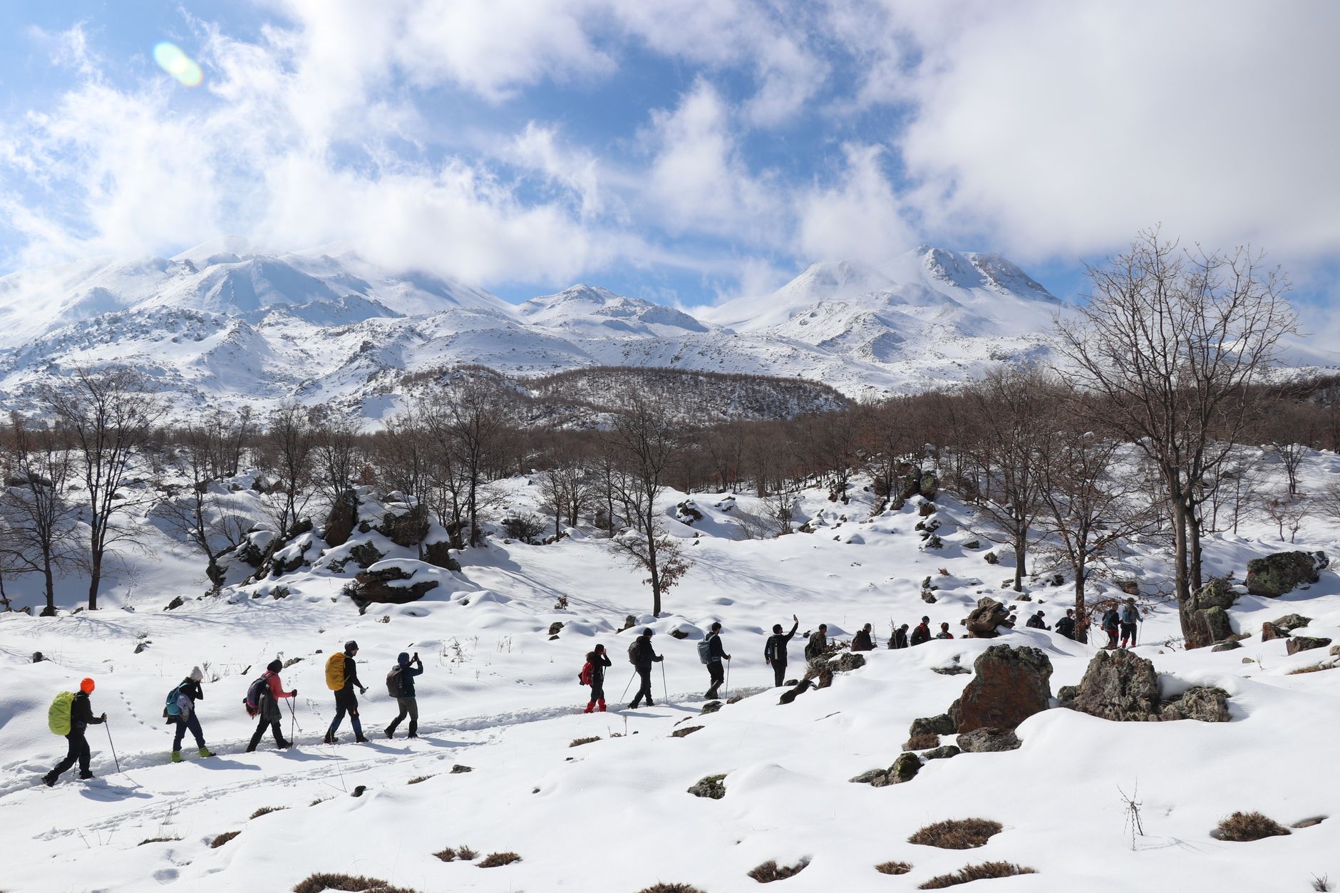 Hikers trekking in snow-covered Taurus Mountains under a blue sky.