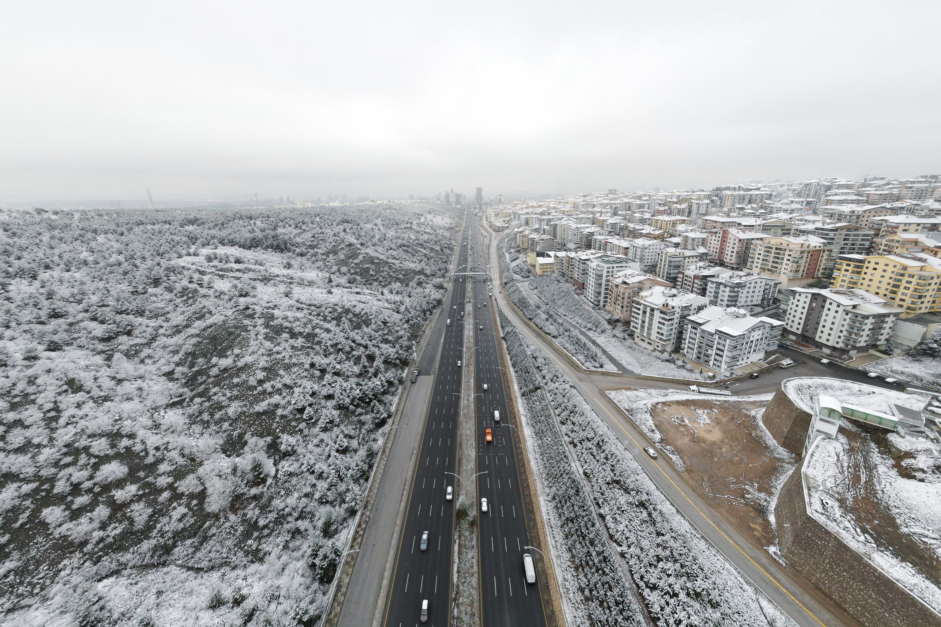 A snowy scene in Ankara, featuring a highway and residential buildings along with a winter landscape.