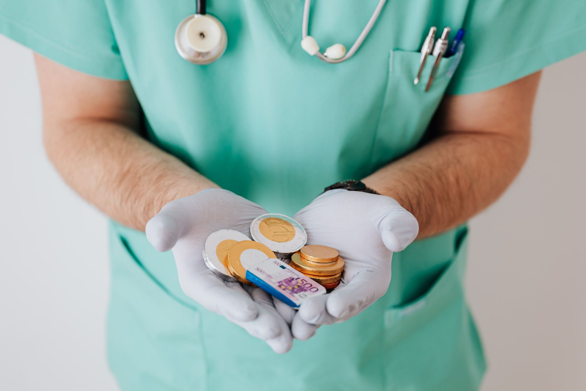 Healthcare worker in scrubs holding coins and a banknote, preparing for medical travel budgeting.