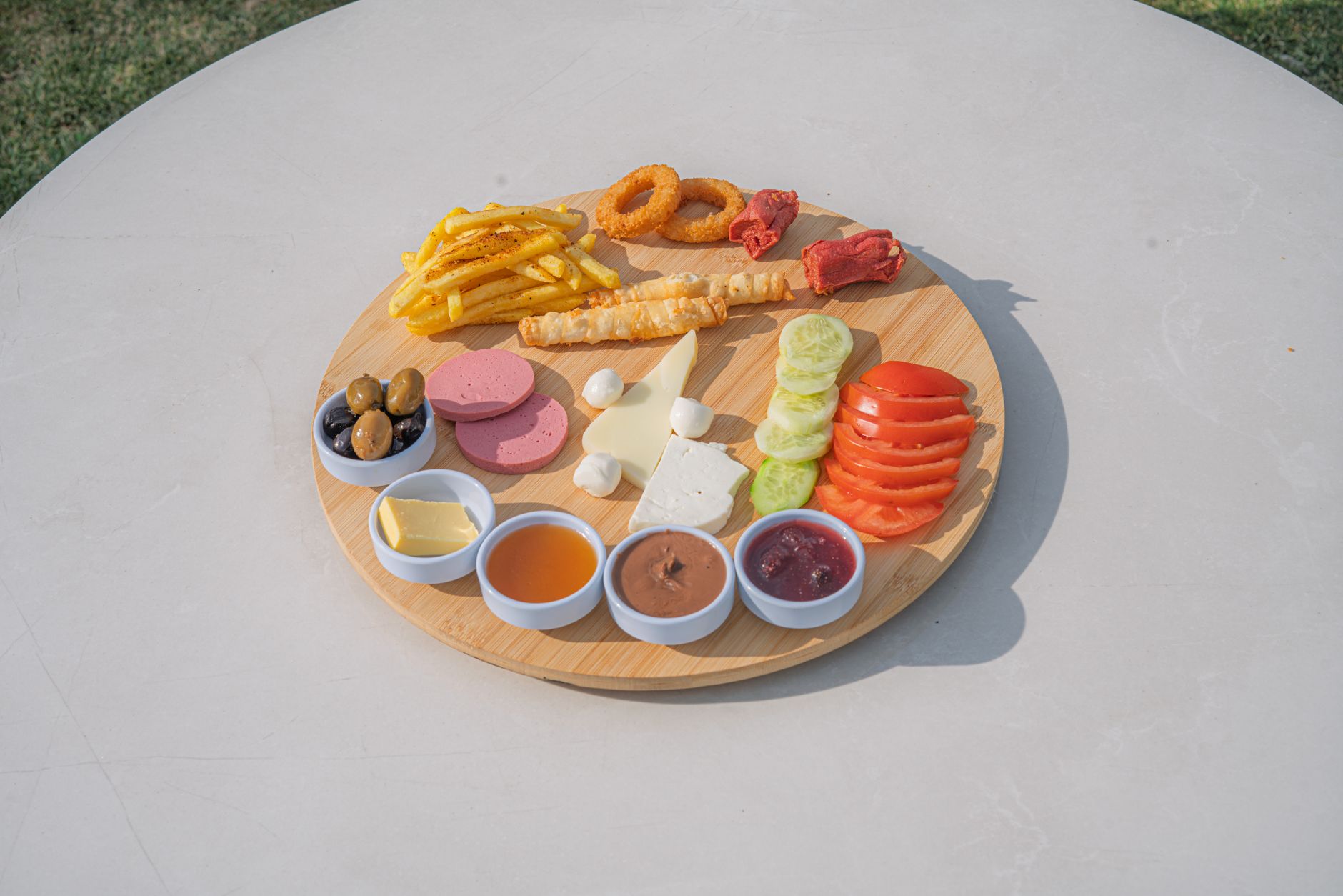 Ahşap bir tepside tulum peyniri, zeytin ve patates kızartması dahil çeşitli yöresel lezzetler.