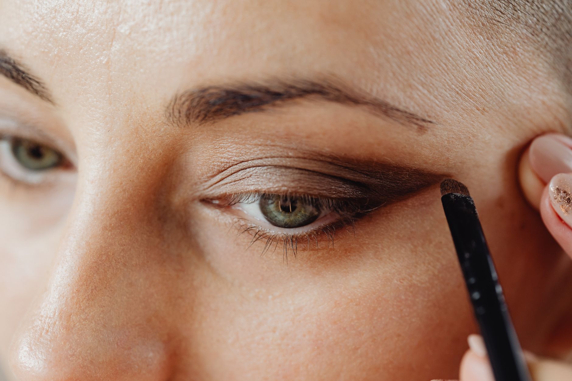 Close-up of a woman's eye during makeup application showcasing natural-looking eyelid results.
