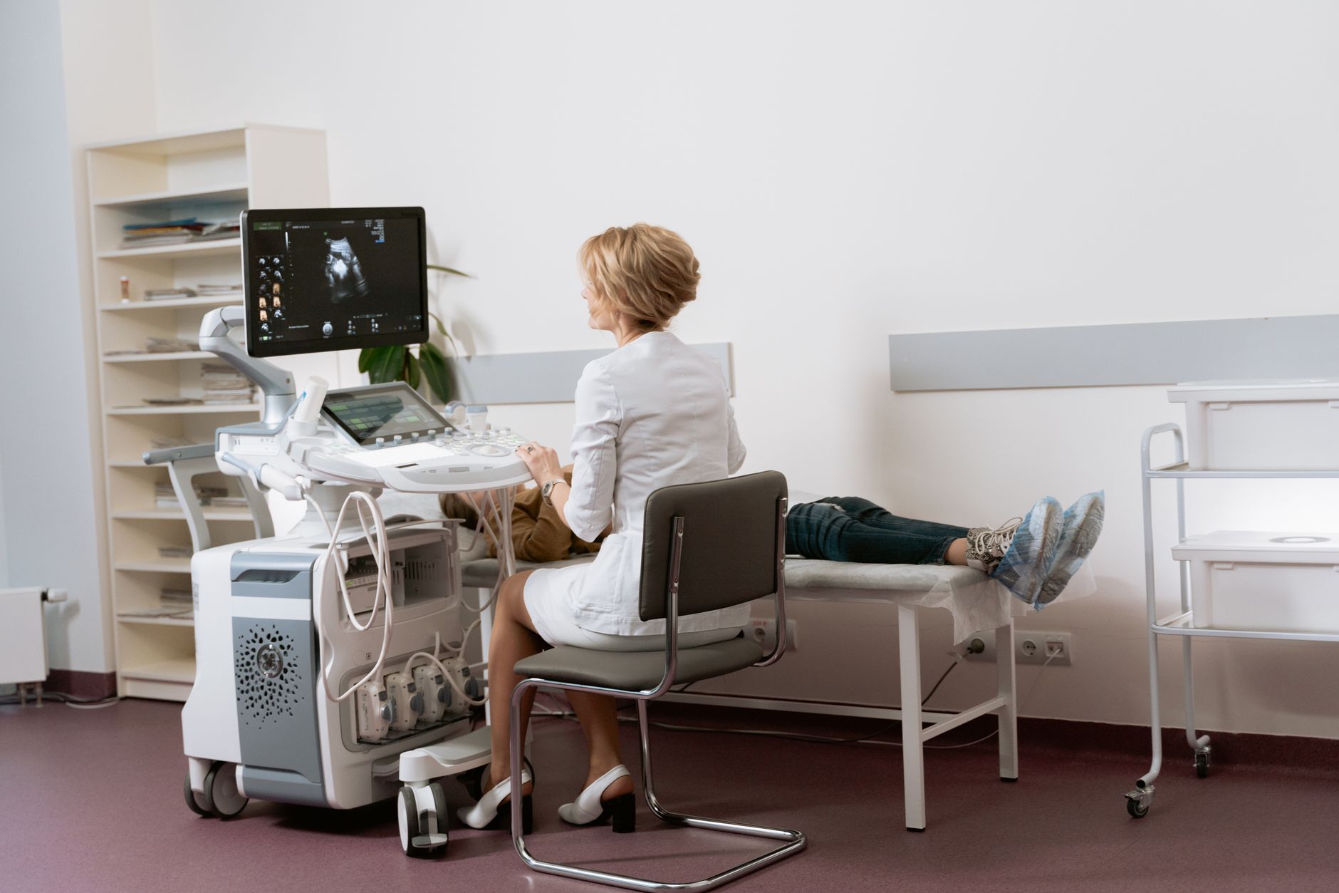A specialist conducting a duplex ultrasound on a patient's leg in a clinical setting.